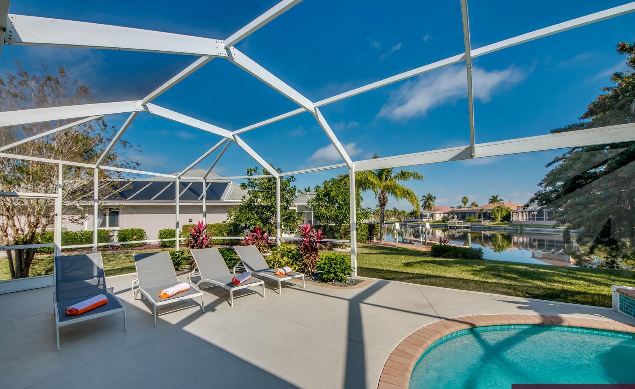 Beheizter Pool mit Sonnenschirm und Strandstühlen am Wasserkanal.