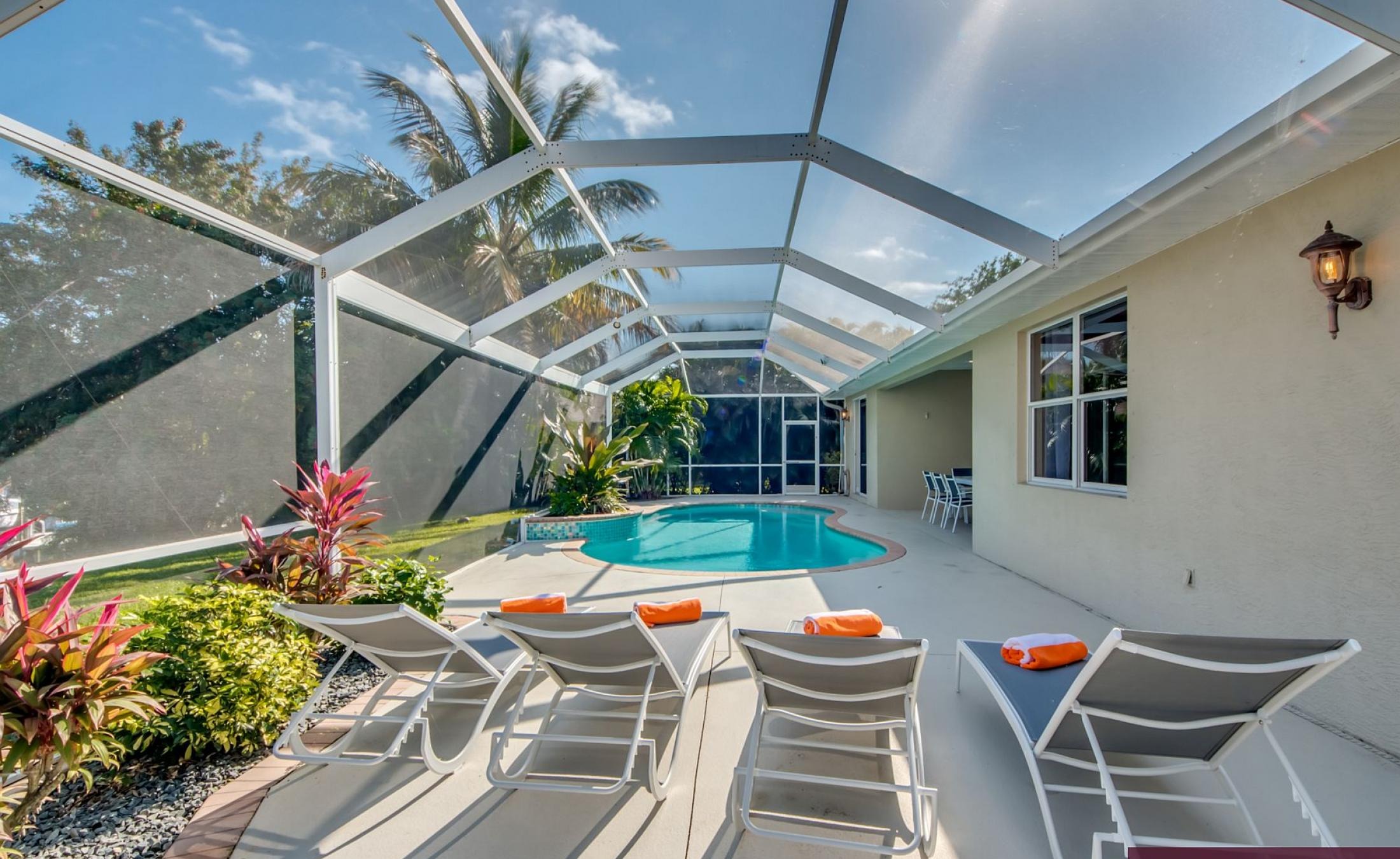 Elektrisch beheizter Pool mit Sonnenschirm und Strandstühlen am Wasserkanal.