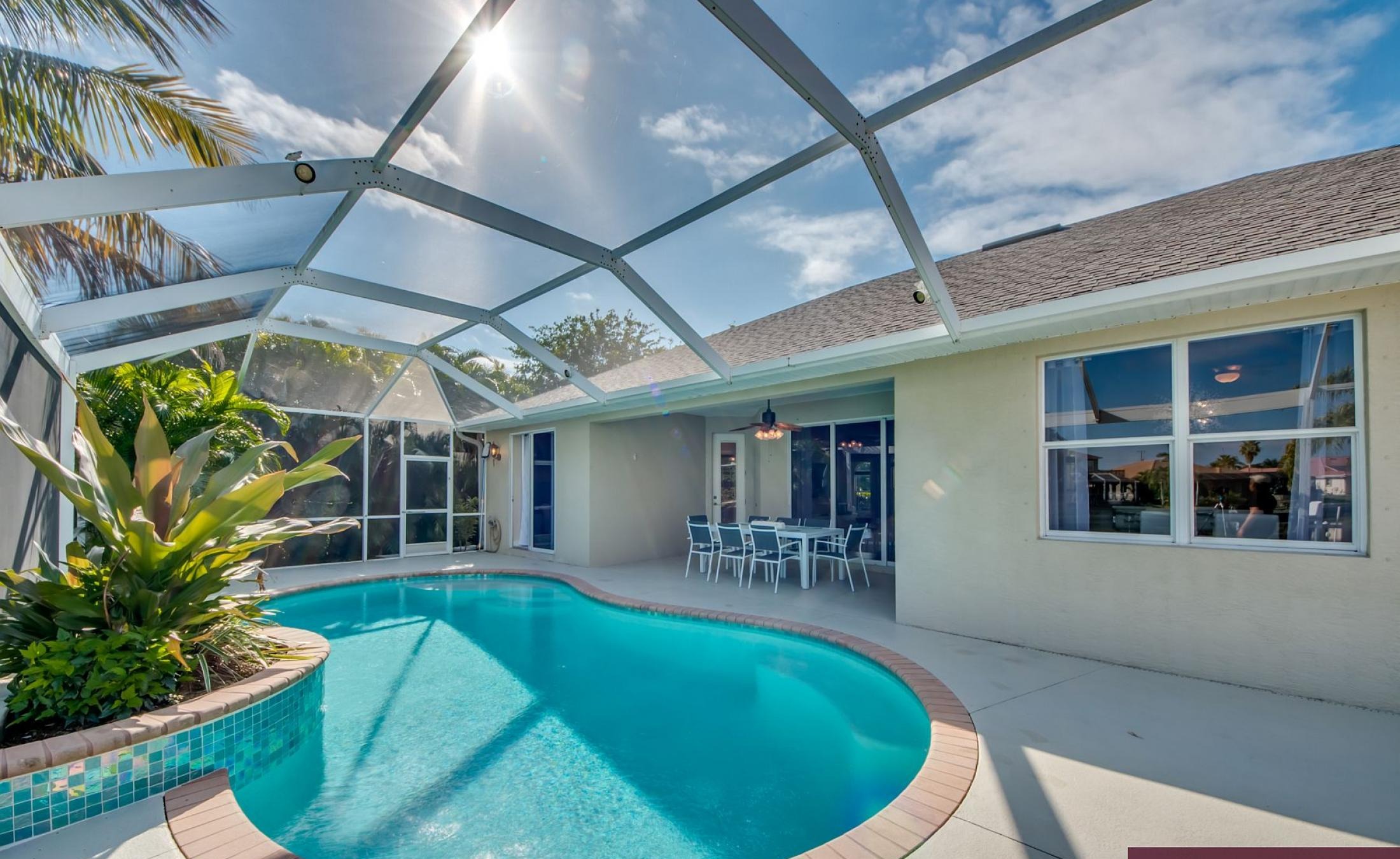 Elektrisch beheizter Pool mit Sonnenschirm und Strandstühlen am Wasserkanal.