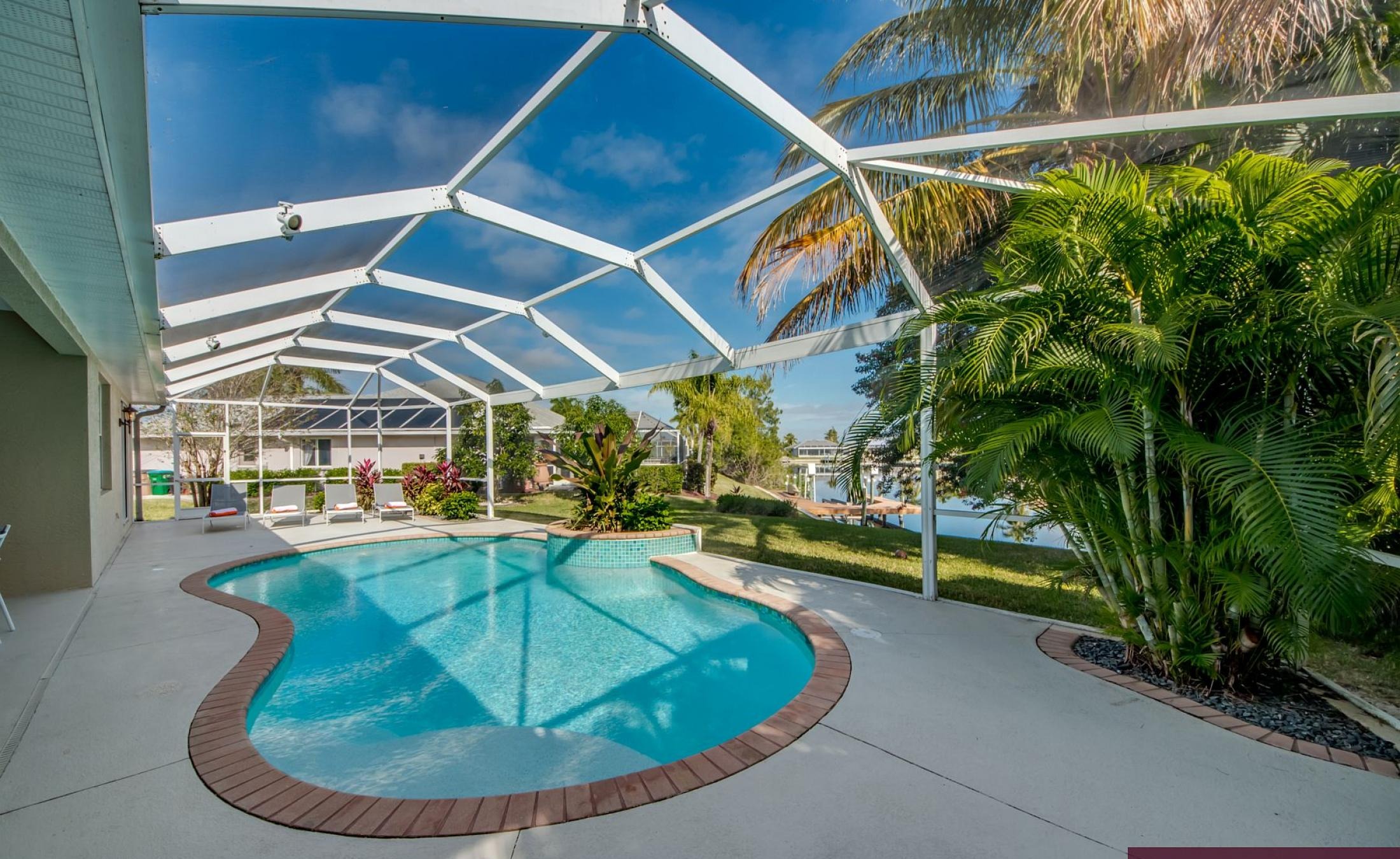 Elektrisch beheizter Pool mit Sonnenschirm und Strandstühlen am Wasserkanal.
