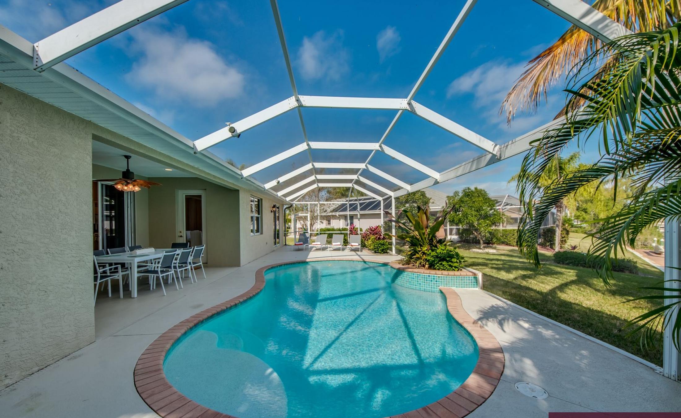 Elektrisch beheizter Pool mit Sonnenschirm und Strandstühlen am Wasserkanal.