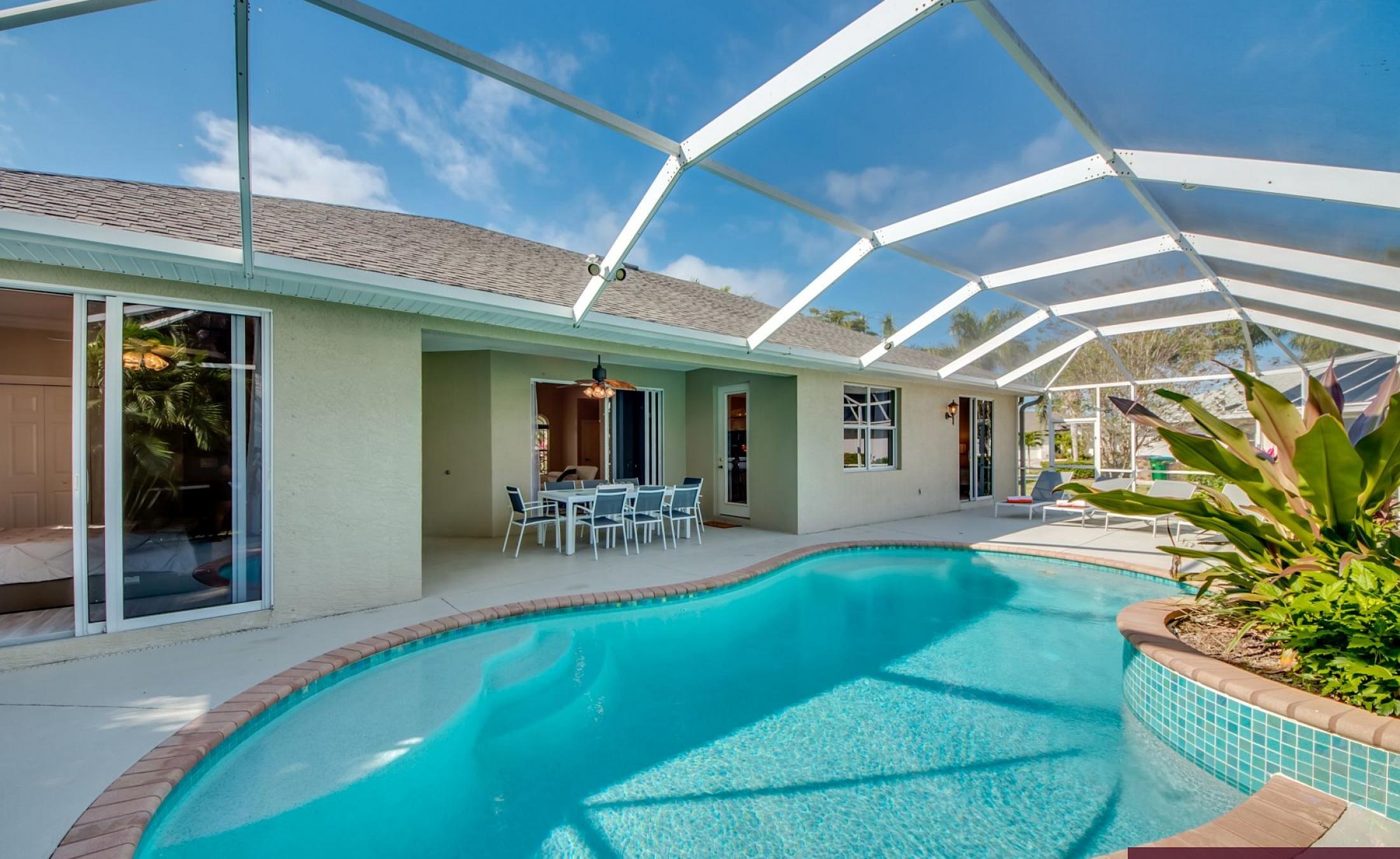 Elektrisch beheizter Pool mit Sonnenschirm und Strandstühlen am Wasserkanal.