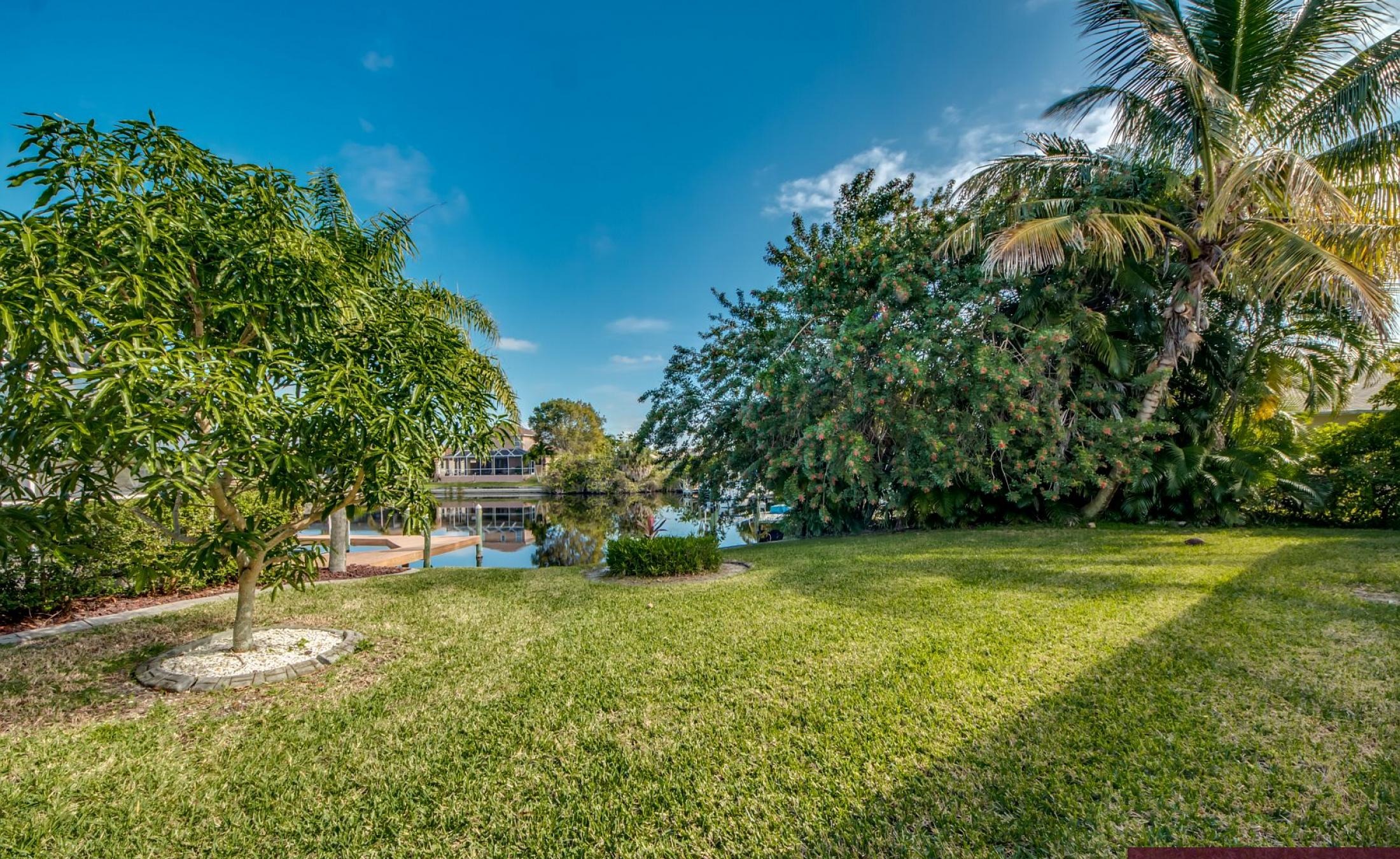 Beheizter Pool mit Sonnenschirm und Strandstühlen am Wasserkanal.