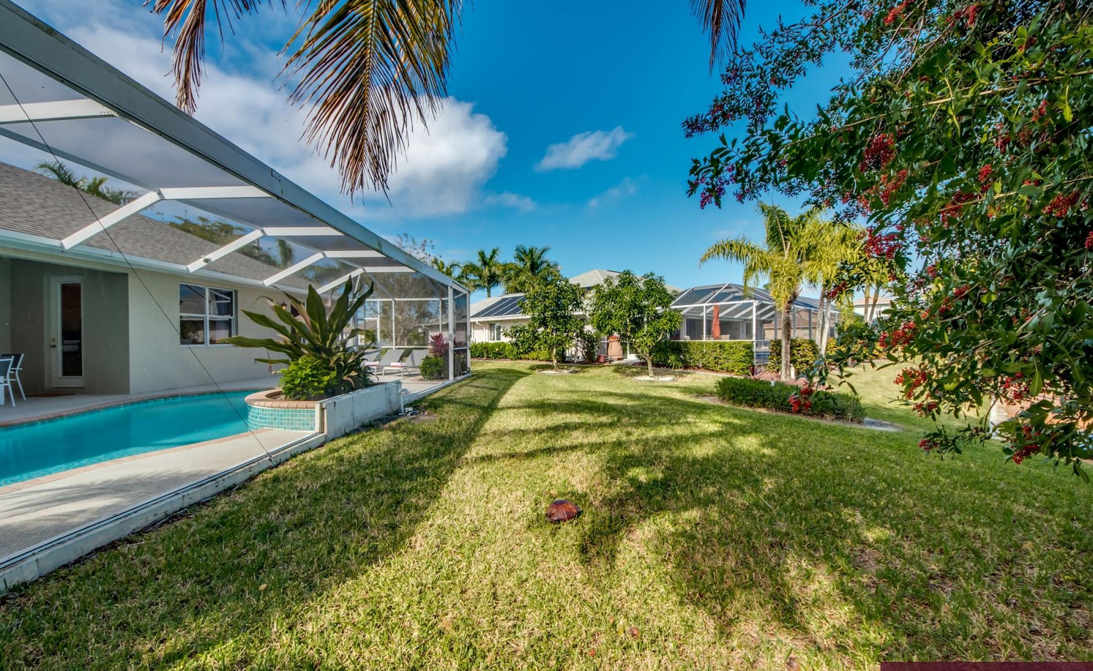 Elektrisch beheizter Pool mit Sonnenschirm und Strandstühlen am Wasserkanal.