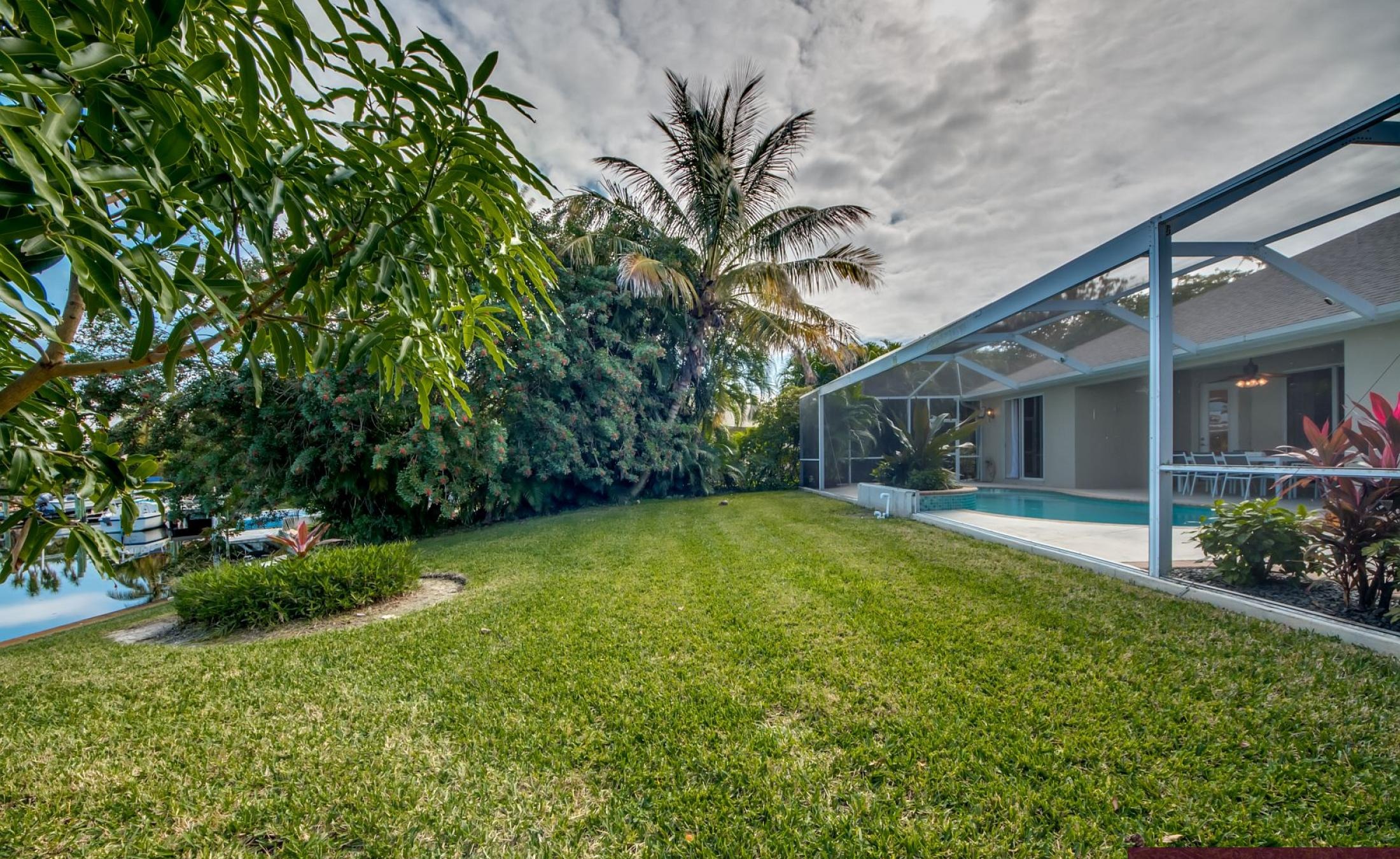 Beheizter Pool mit Sonnenschirm und Strandstühlen am Kanal.