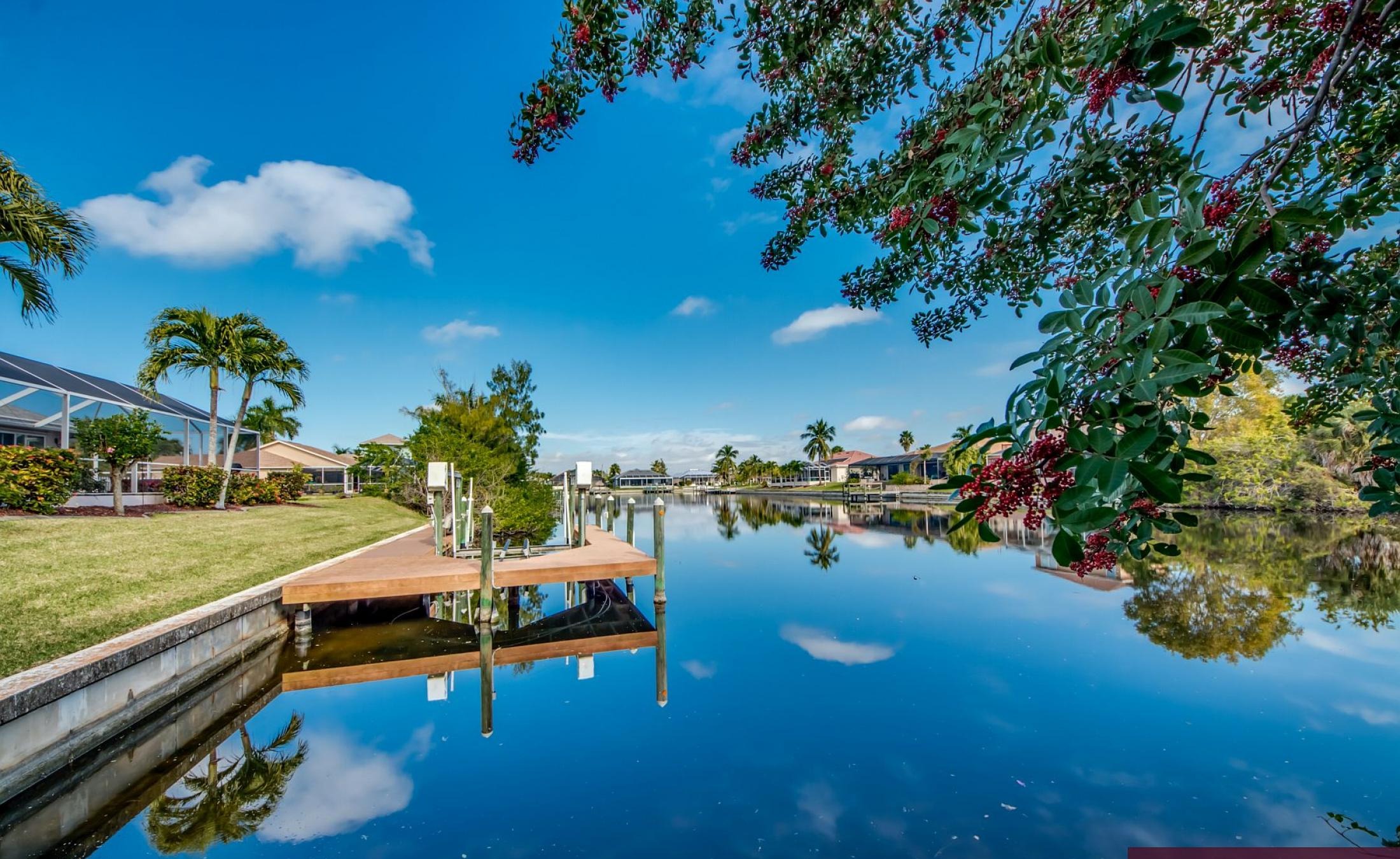 Elektrisch beheizter Pool mit Sonnenschirm und Strandstühlen am Wasserkanal.