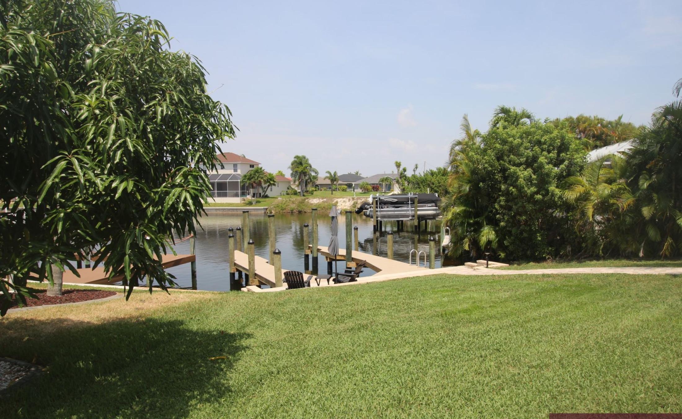 Beheizter Pool mit Sonnenschirm und Strandstühlen am Wasserkanal.