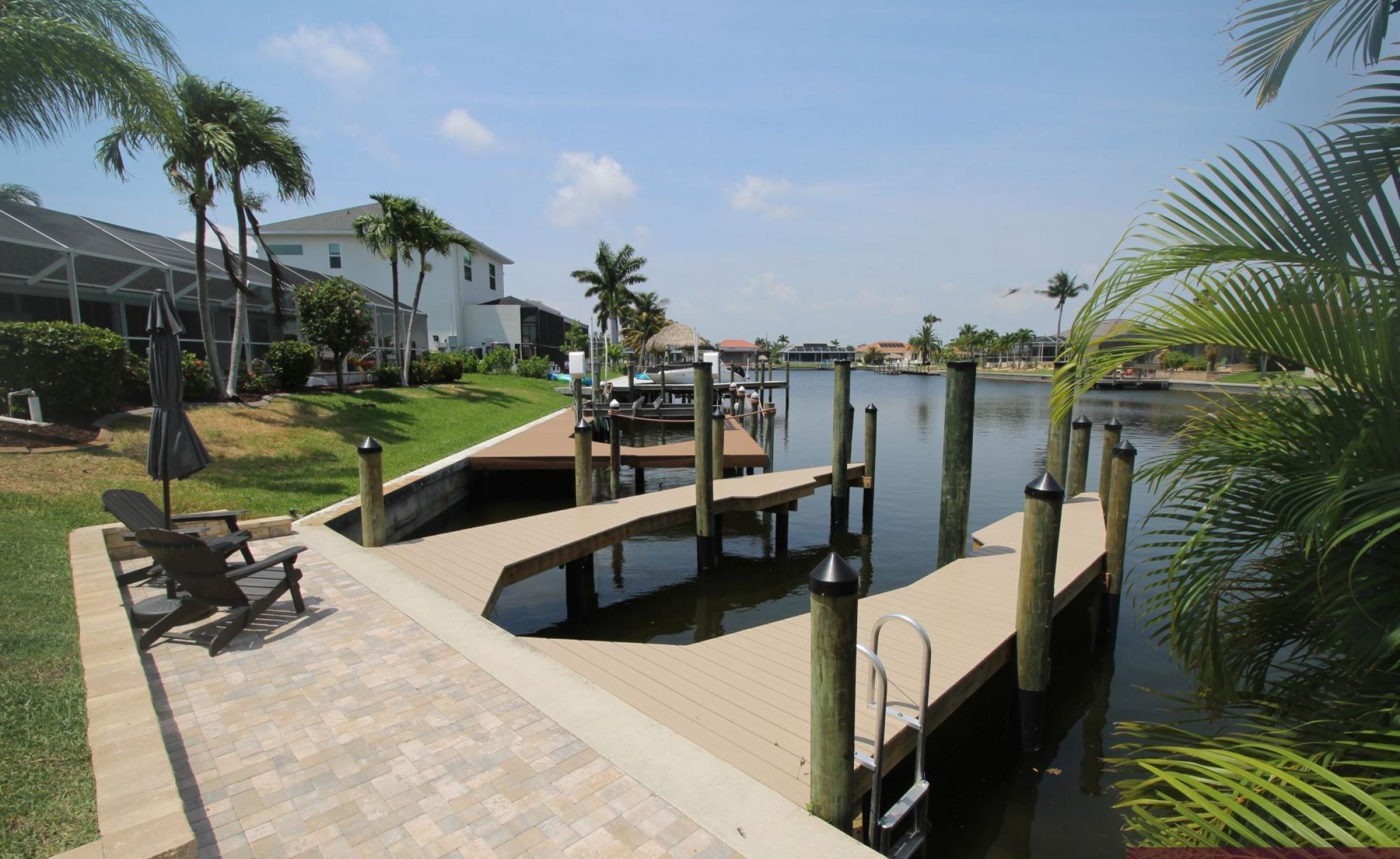 Beheizter Pool mit Sonnenschirm und Strandstühlen am Wasserkanal.