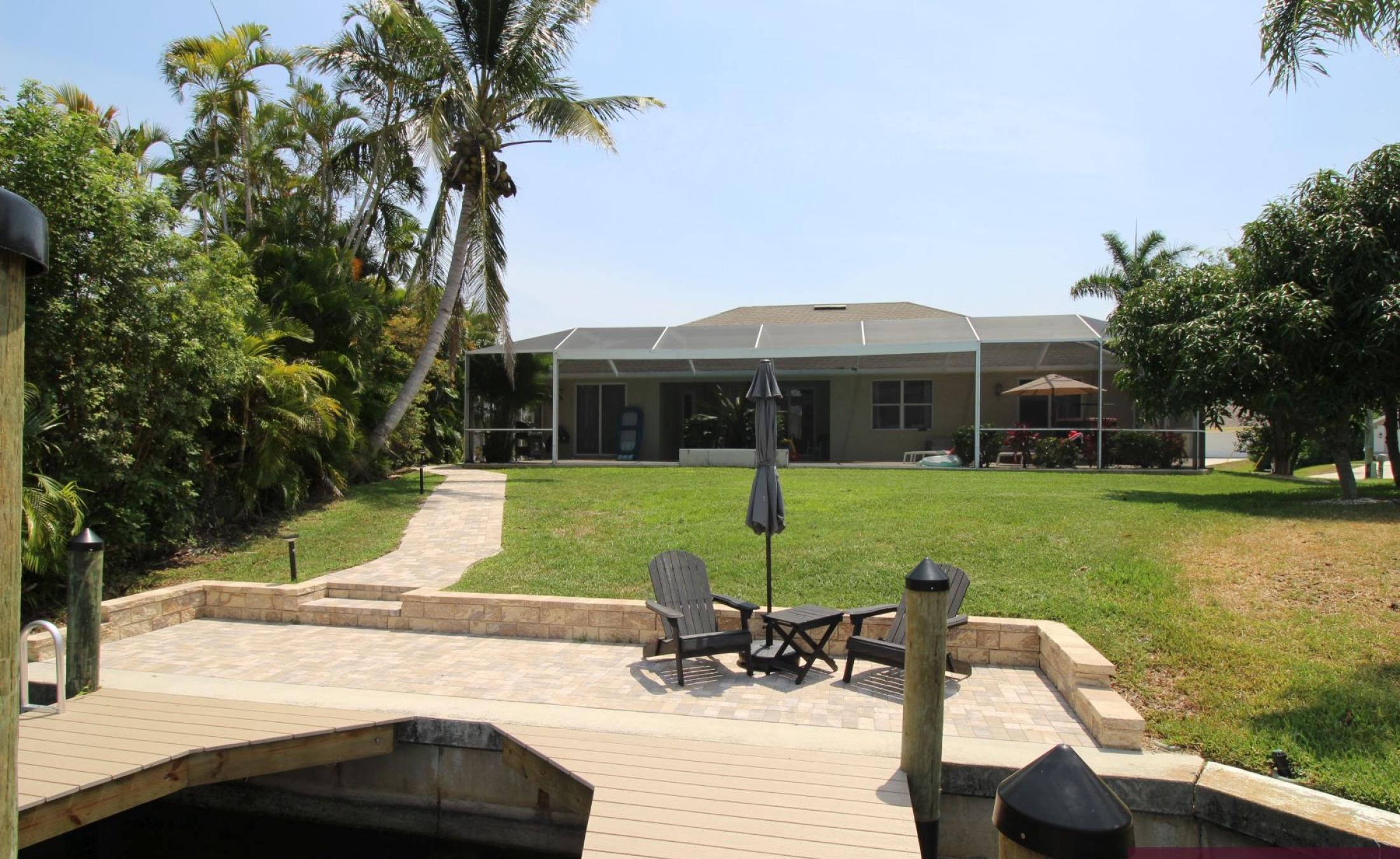 Beheizter Pool mit Sonnenschirm und Strandstühlen am Wasserkanal.