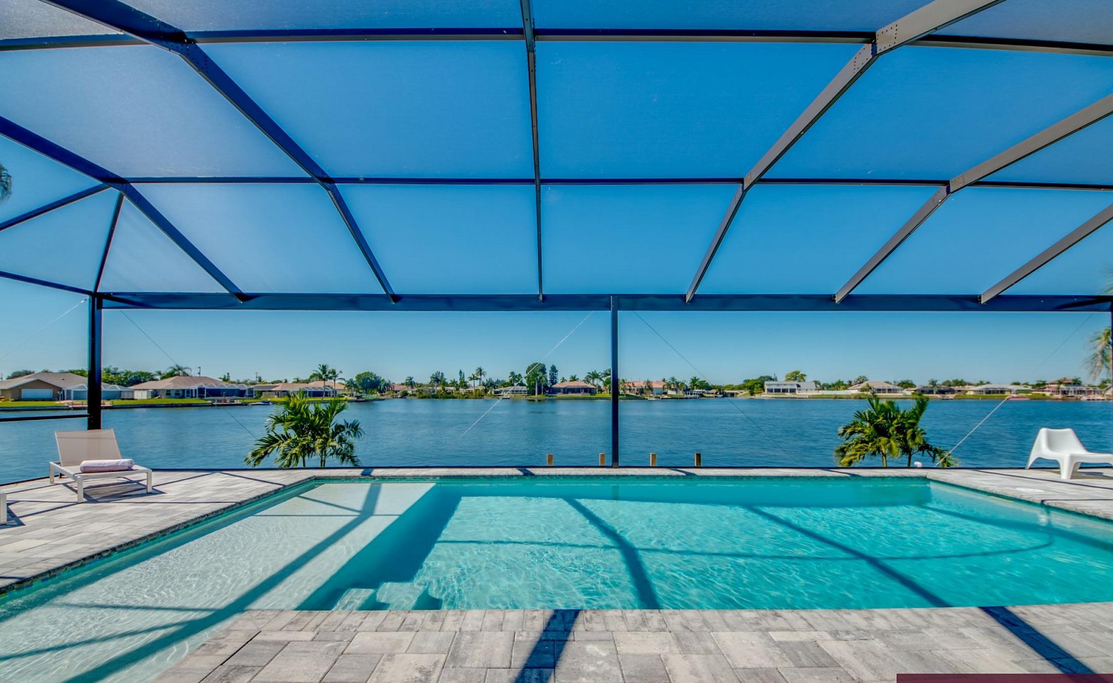 Beheizter Pool mit Sunledge und Liegen am Seeufer.