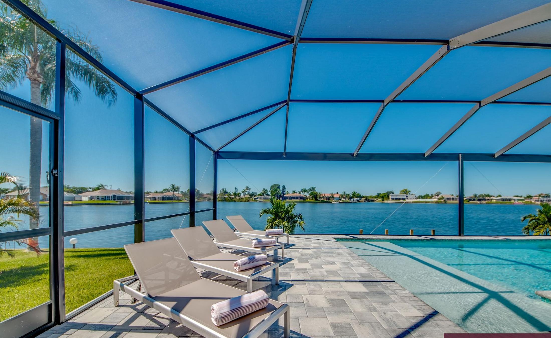 Beheizter Pool mit Sunledge und Liegen am Seeufer.