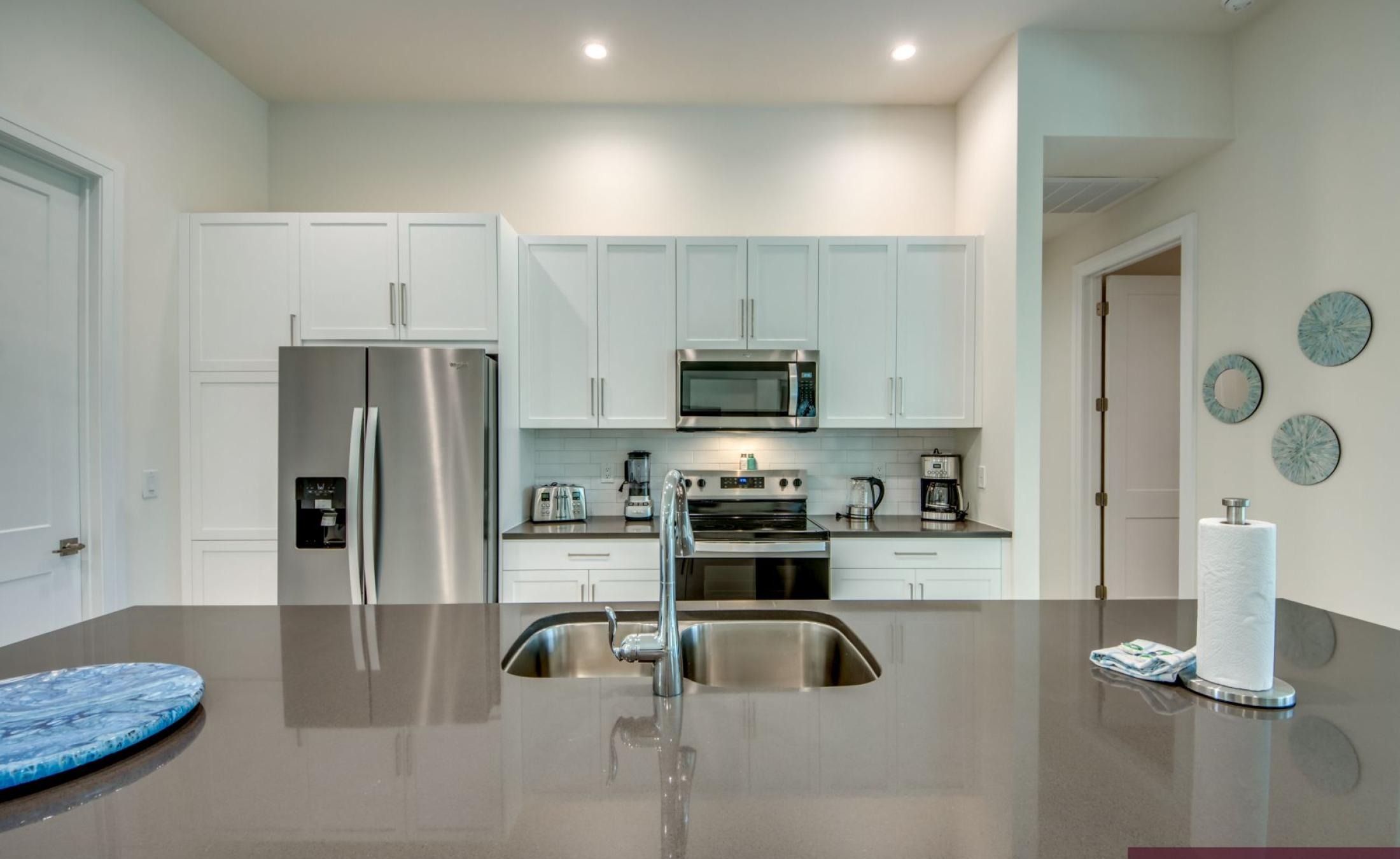 Modernes Wohnzimmer mit offener Küche und großen Fensterfronten.