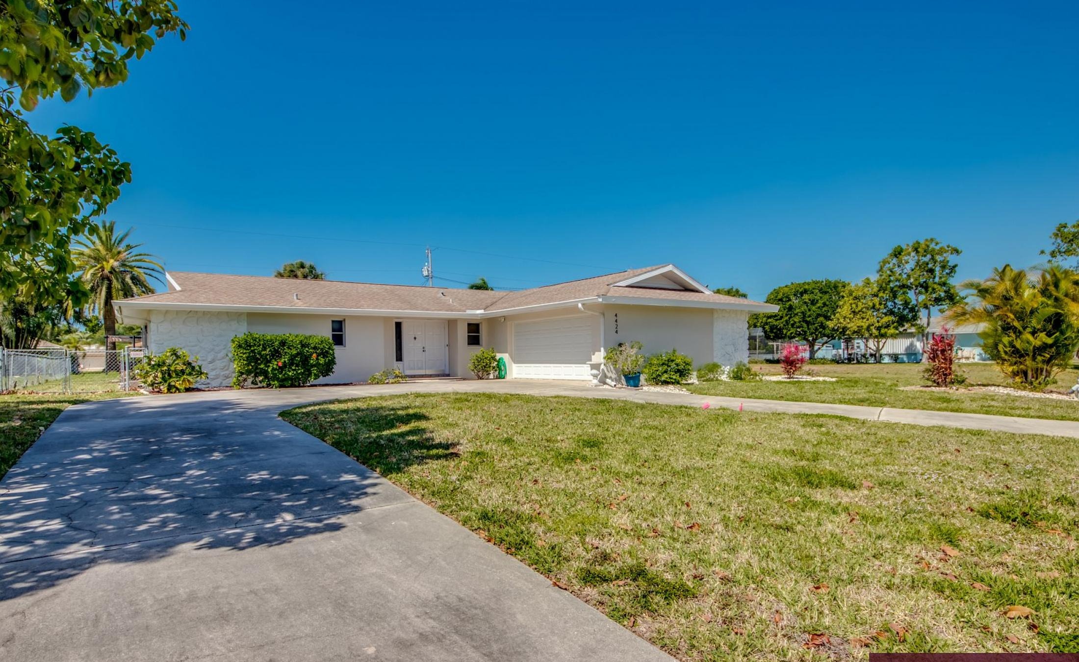 Moderne Villa mit sonniger Poolterrasse und großen Glasschiebetüren.