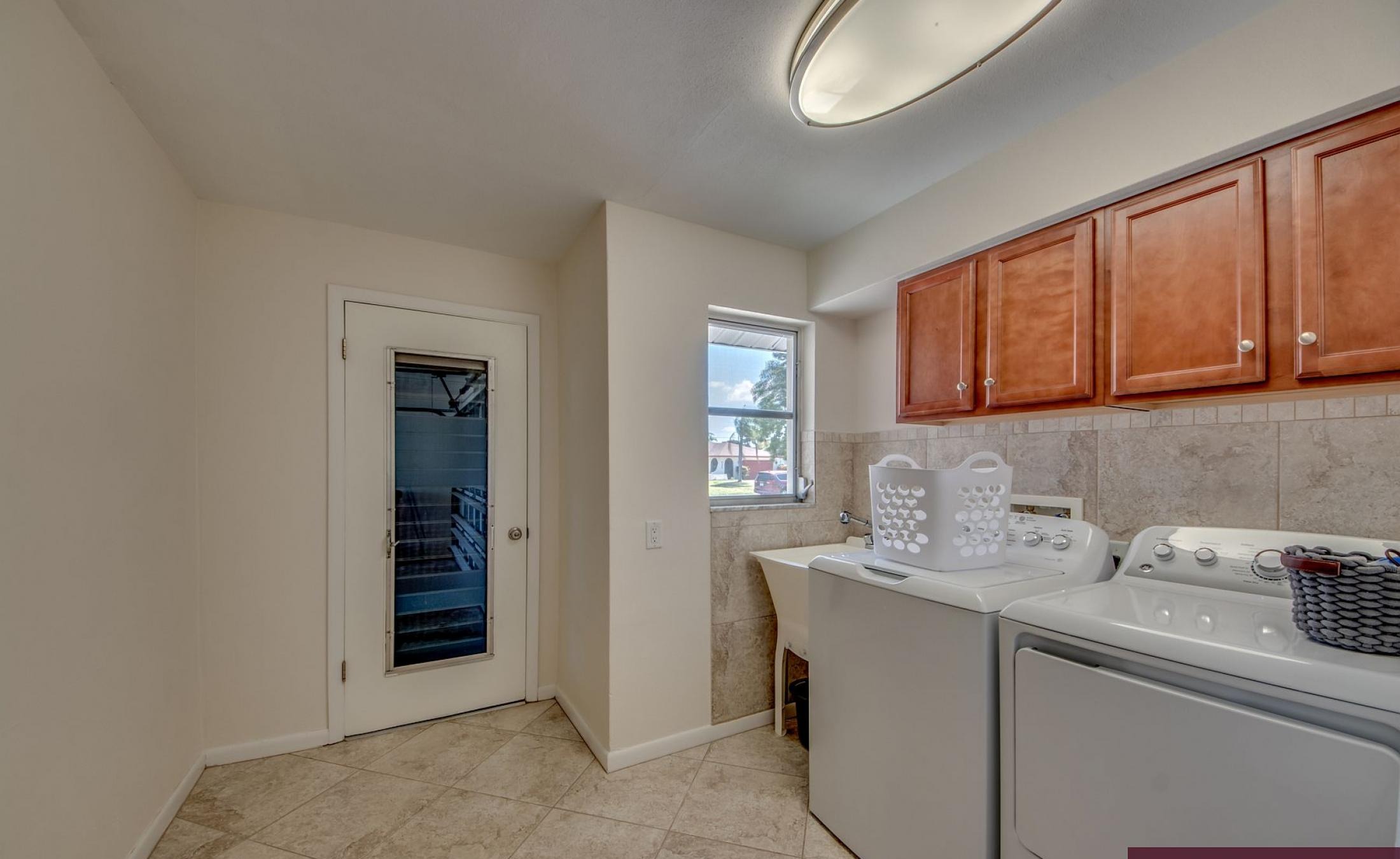 Moderne Villa mit sonniger Poolterrasse und großen Glasschiebetüren.