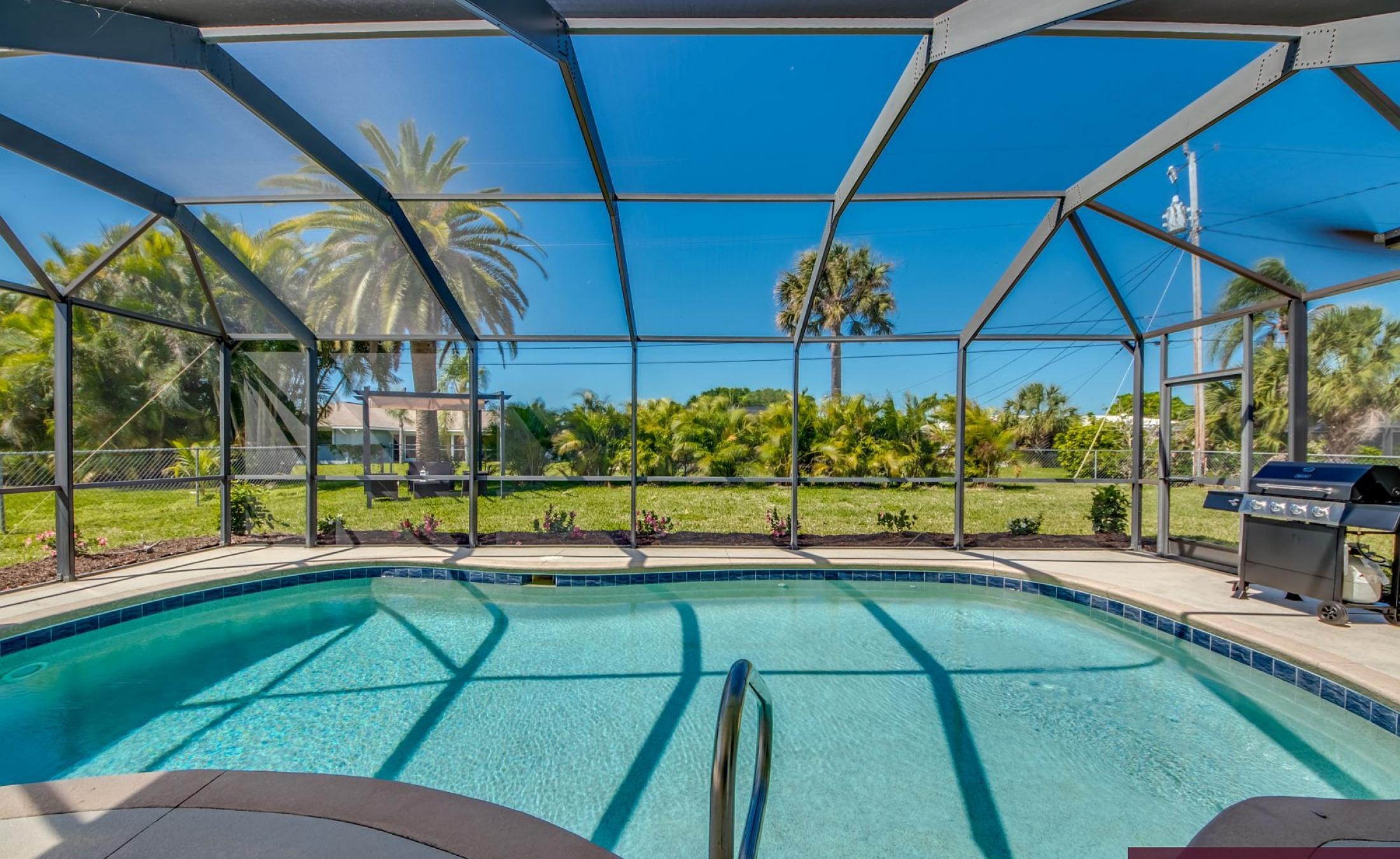 Sonnige Poolterrasse mit beheiztem Pool und Grillbereich.