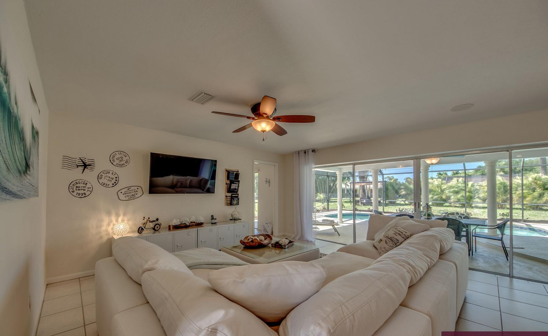 Moderne Villa in Cape Coral mit sonniger Poolterrasse und großen Glasschiebetüren.