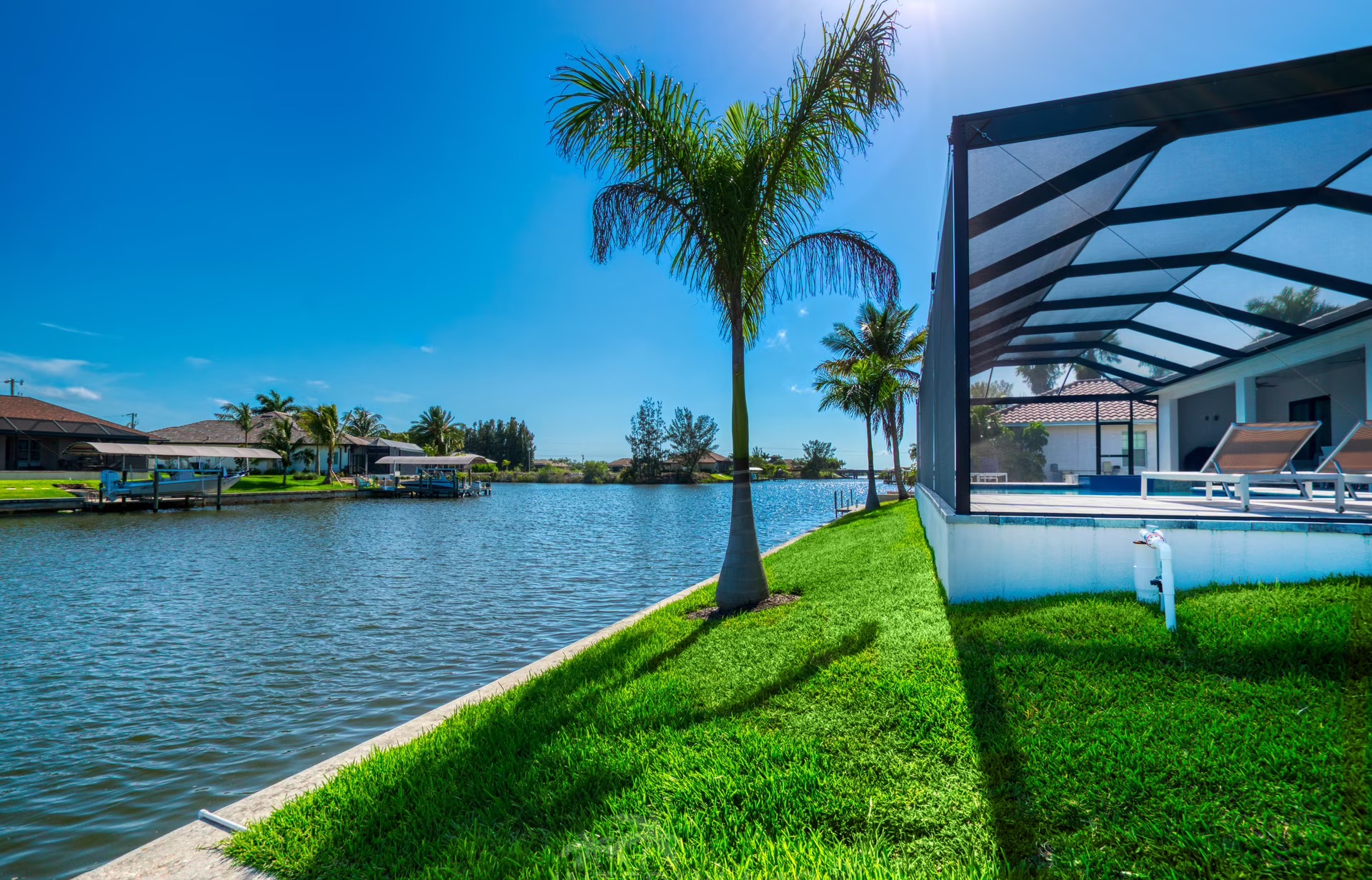 Überdachter Sitzbereich am Kanal mit Gartenmöbeln und Blick aufs Wasser.