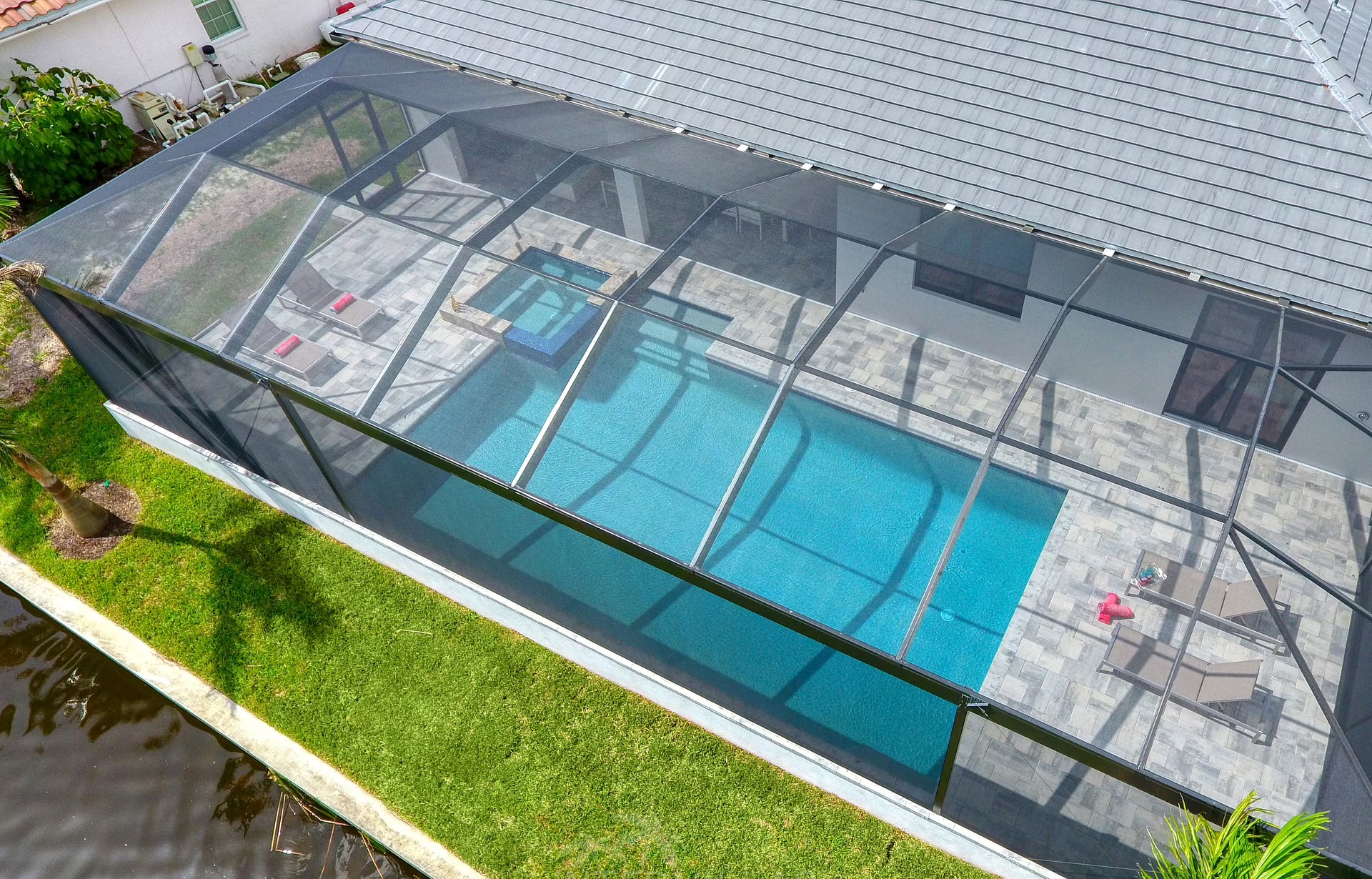 Überdachter Sitzbereich am Pool mit Gasgrill und Gartenmöbeln.