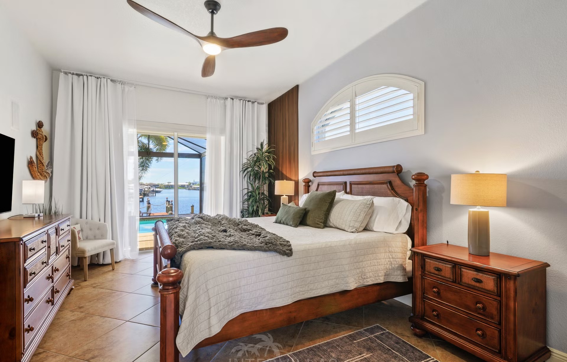 Überdachte Lanai mit Sitzbereich, Outdoor-Küche und Blick auf Kanal und beheizten Pool.