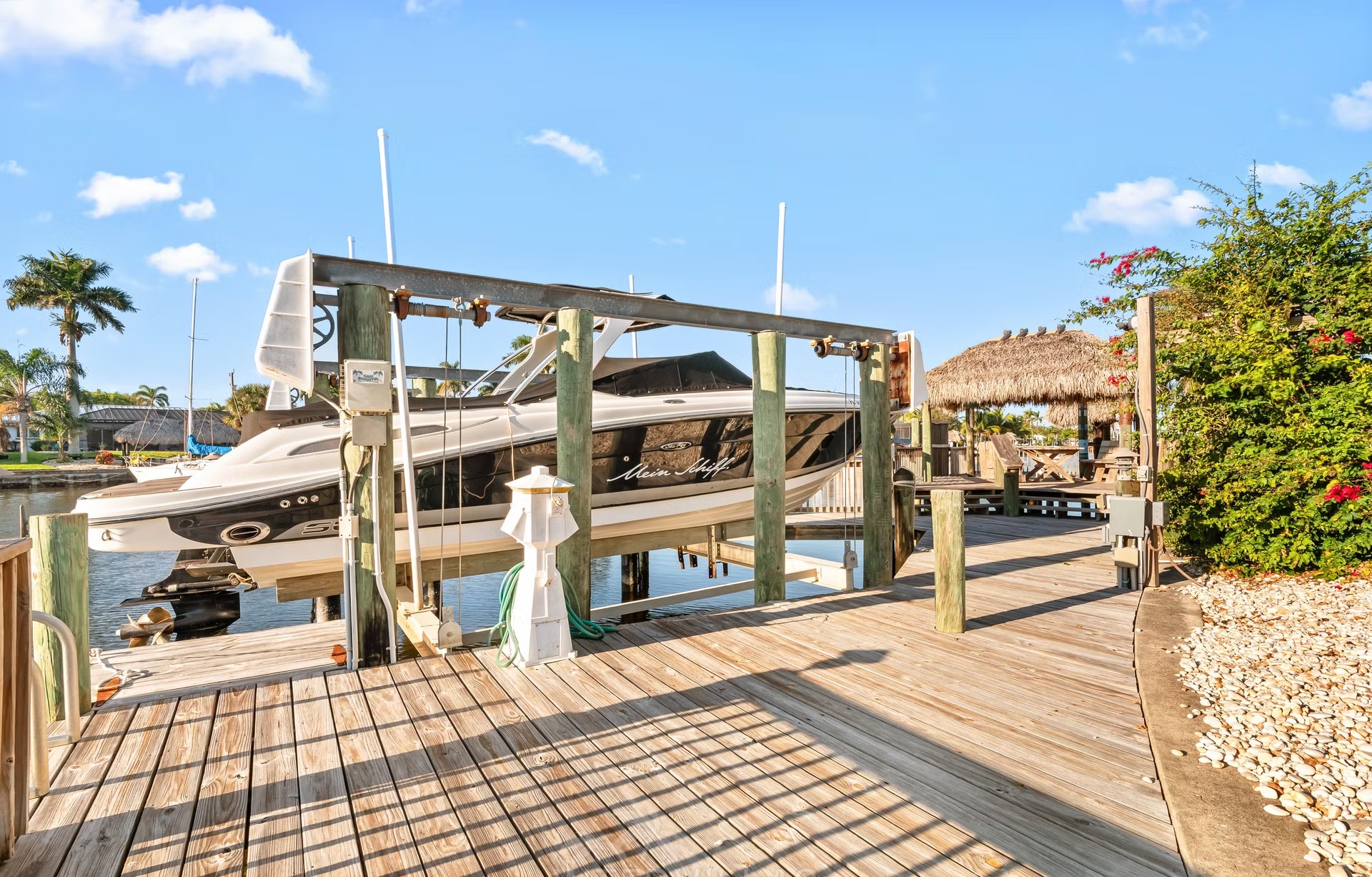 Privates Bootsdock am Kanal mit Tiki-Hut und Sitzbereich.