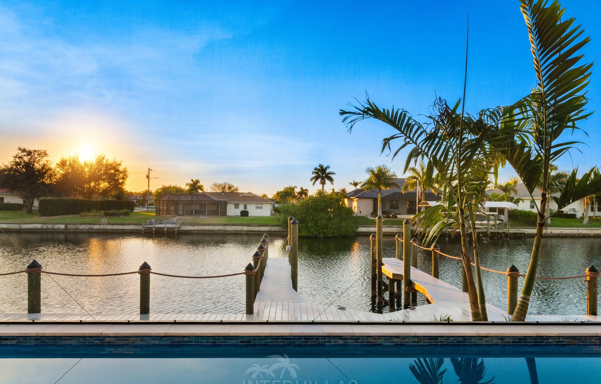 Moderne Villa am Kanal mit Salzwasserpool und Outdoor-Spa bei Sonnenuntergang.