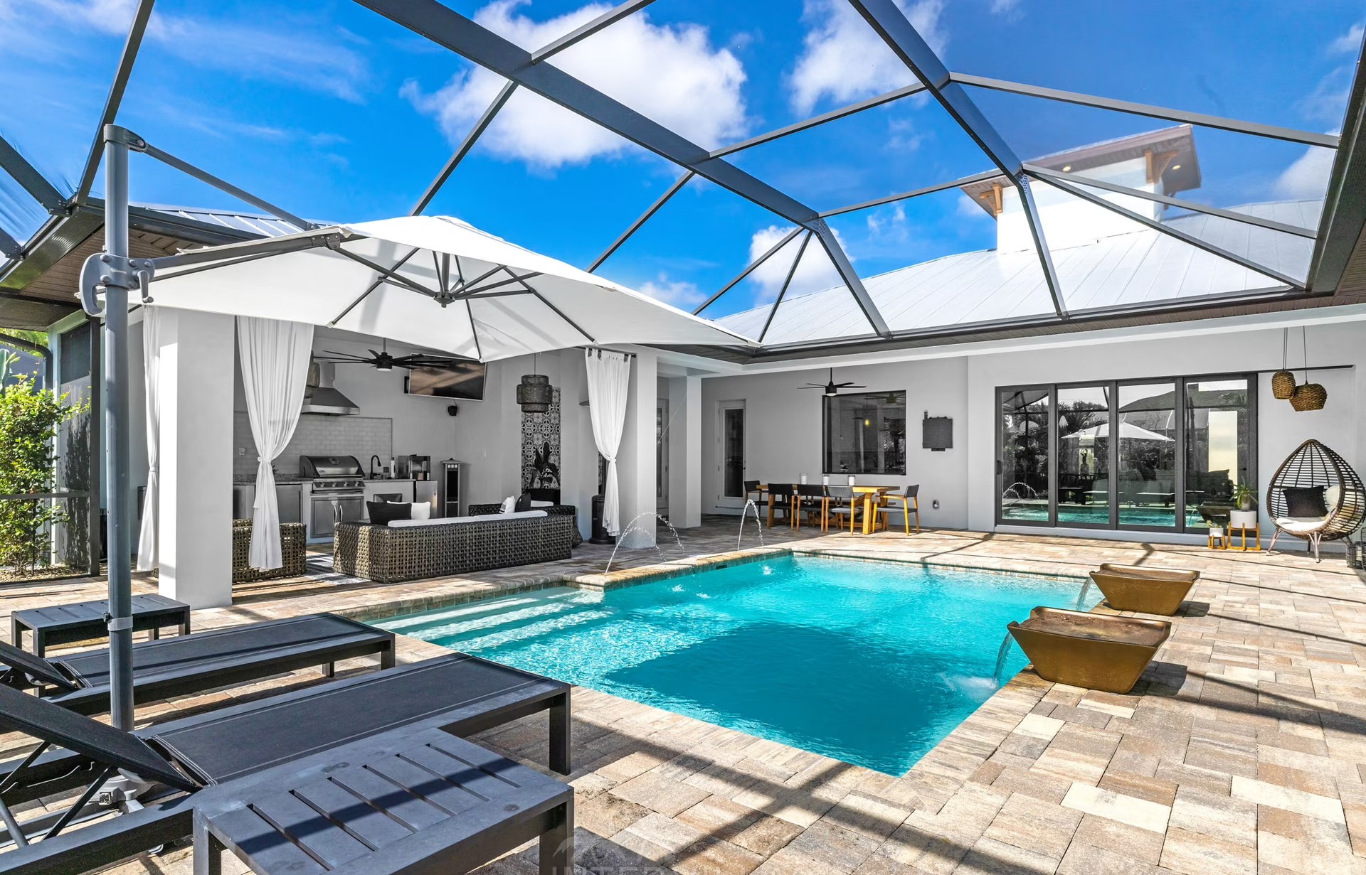 Moderner Poolbereich mit beheiztem Pool, Outdoor-Küche und überdachtem Sitzplatz.