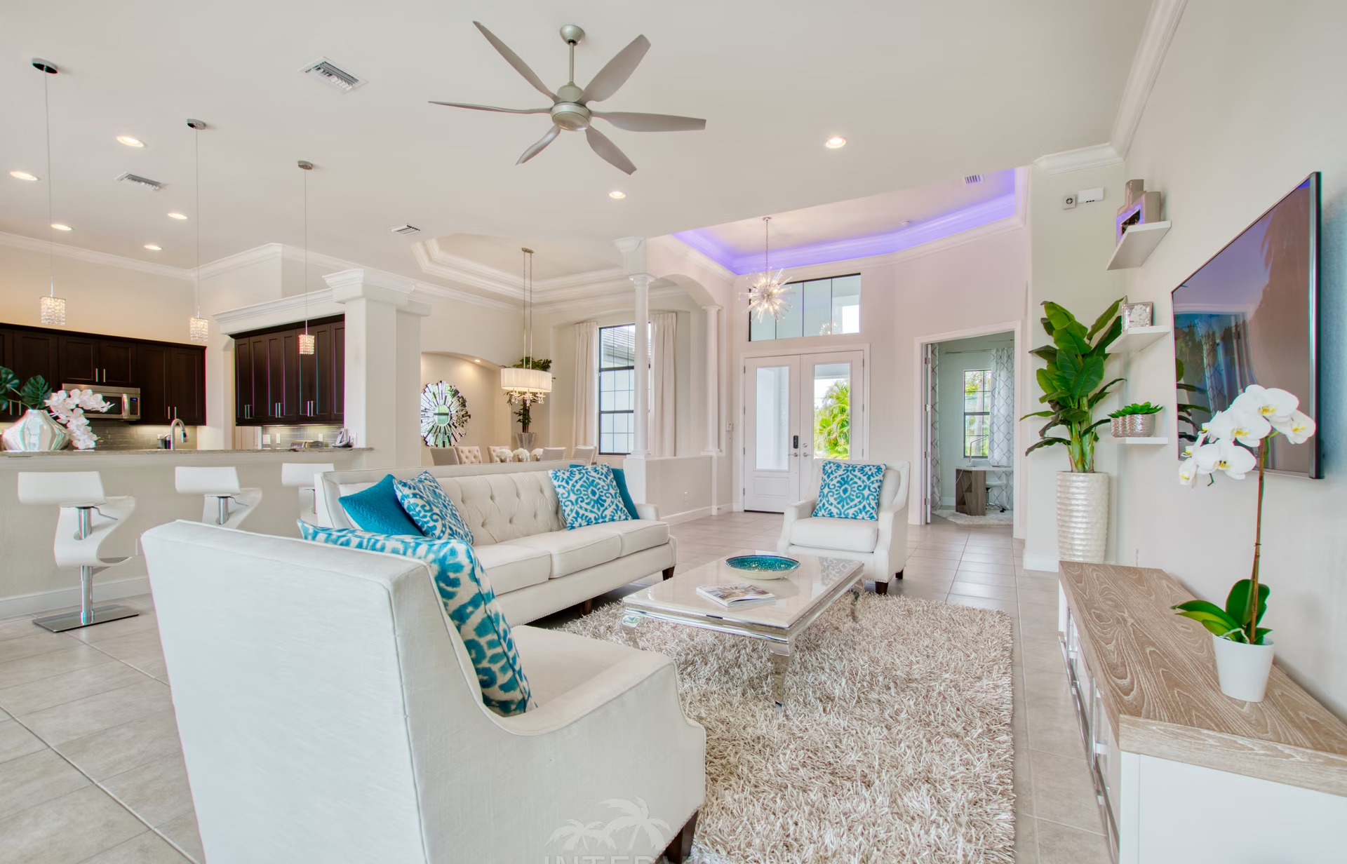 Heller Wohnbereich mit offener Küche und Blick auf den Poolbereich.