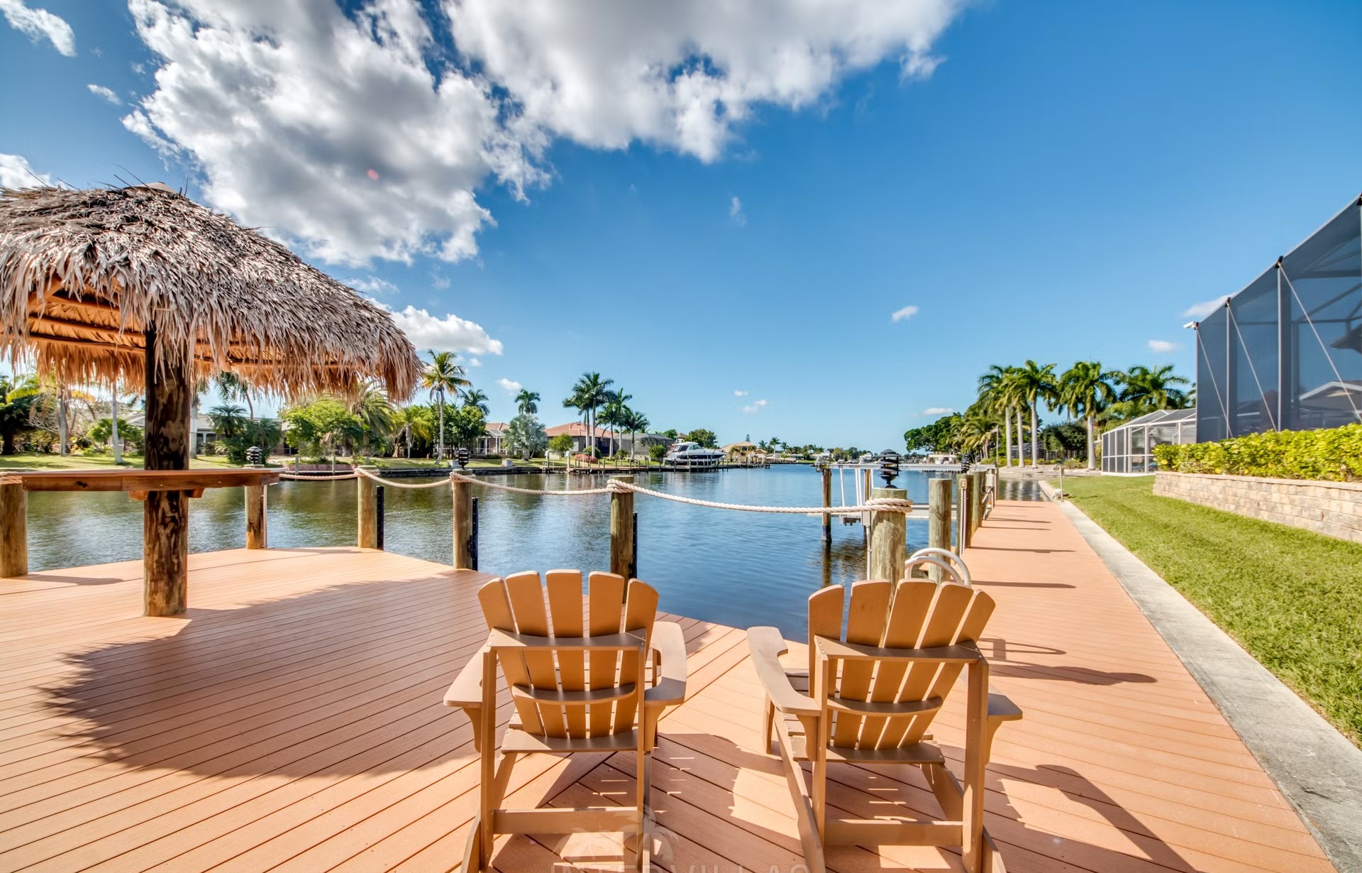 Dock am Kanal mit Tiki-Hut und Kajaks am Wasser.