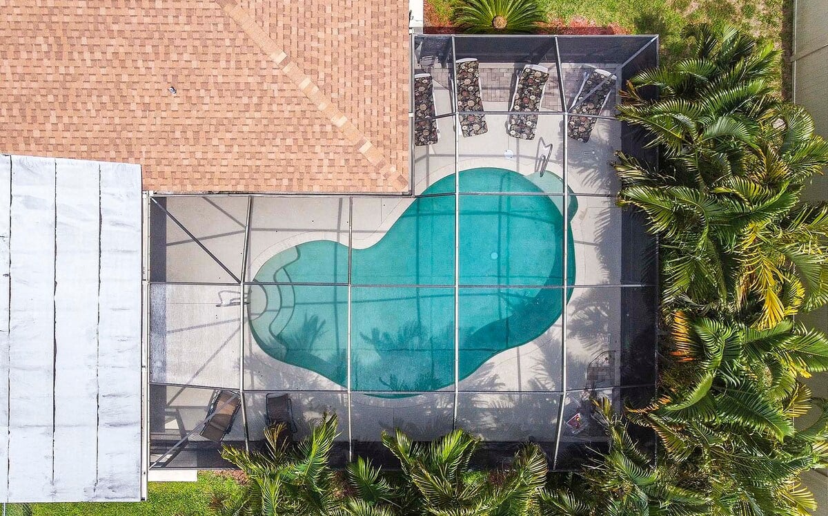 Sonnige Poolterrasse mit beheiztem Pool, Grill und Sitzbereich im eingezäunten Garten.