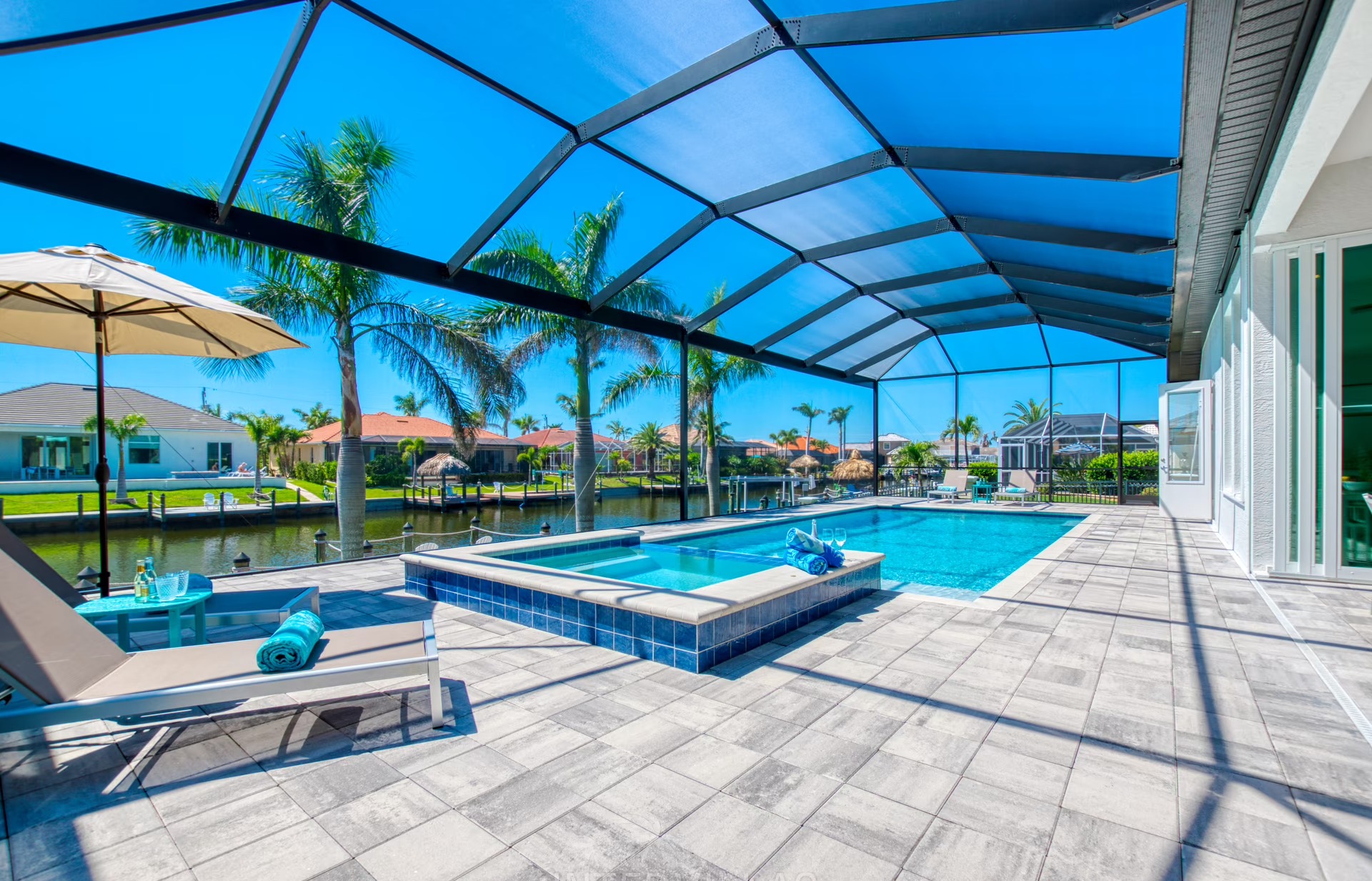 Moderner Poolbereich mit Jacuzzi, Liegen und überdachter Terrasse am Kanal.