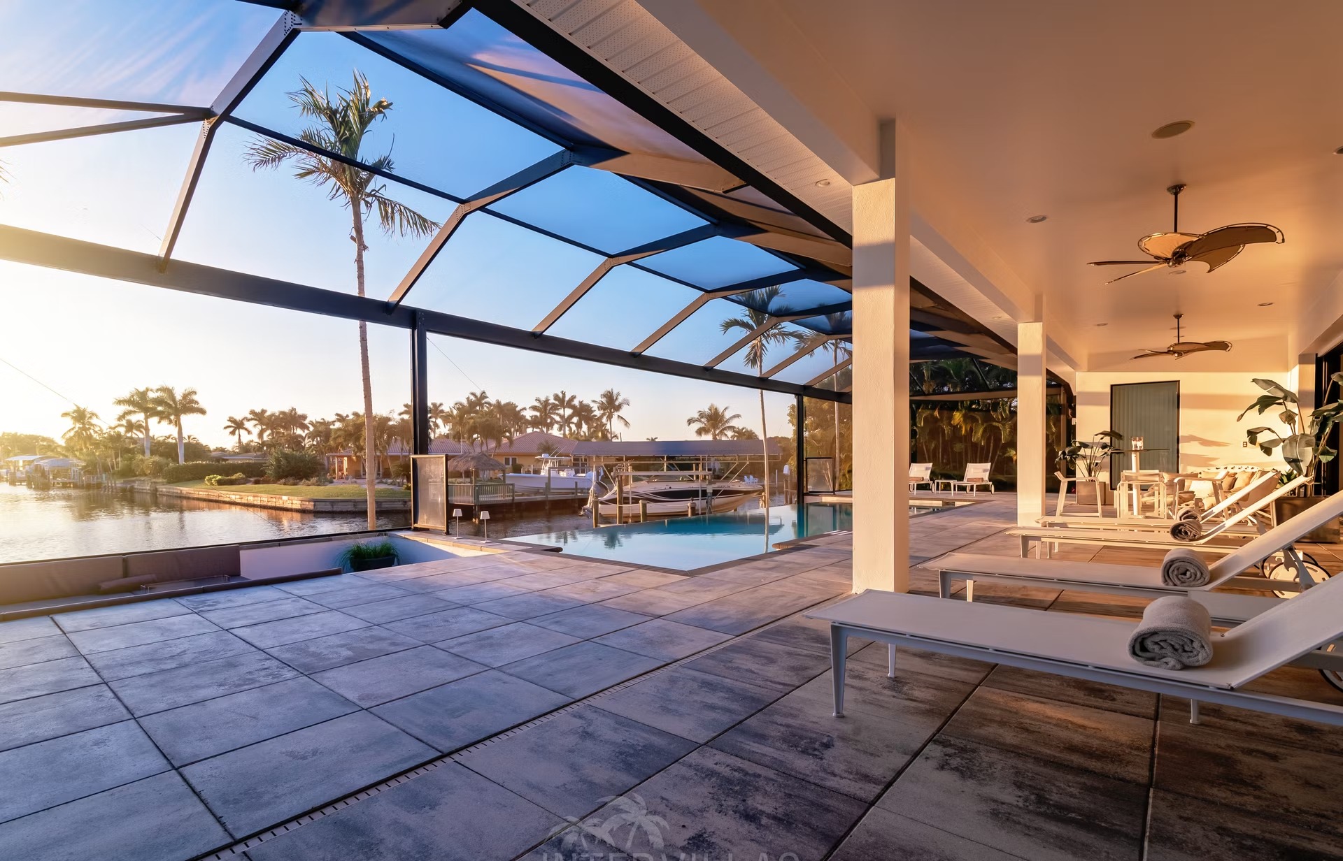 Infinity-Salzwasserpool mit Sonnenliegen und Blick aufs Wasser bei Sonnenuntergang.