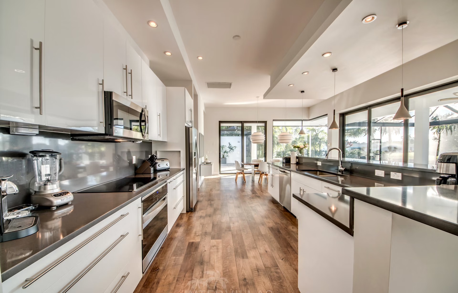 Infinity-Salzwasserpool mit Sonnenliegen und Blick auf den Kanal bei Sonnenuntergang.