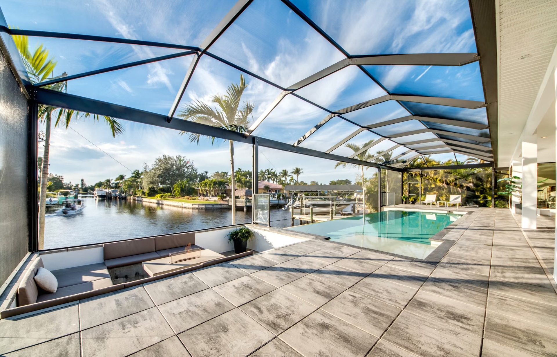Infinity-Salzwasserpool am Wasser mit Sonnenliegen und Blick auf den Sonnenuntergang.