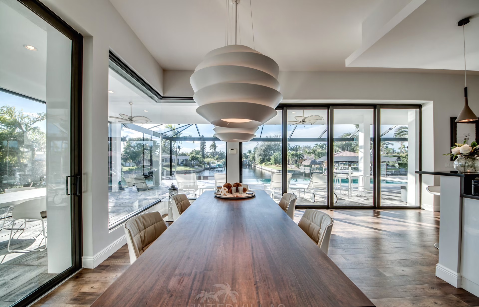Infinity-Salzwasserpool mit Sonnenliegen und Blick auf den Kanal bei Sonnenuntergang.