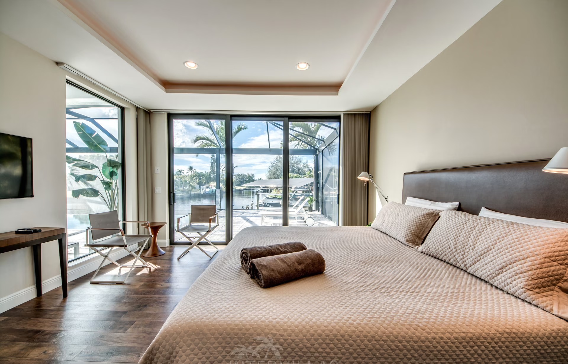 Infinity-Salzwasserpool mit Sonnenliegen und Blick auf den Kanal bei Sonnenuntergang.