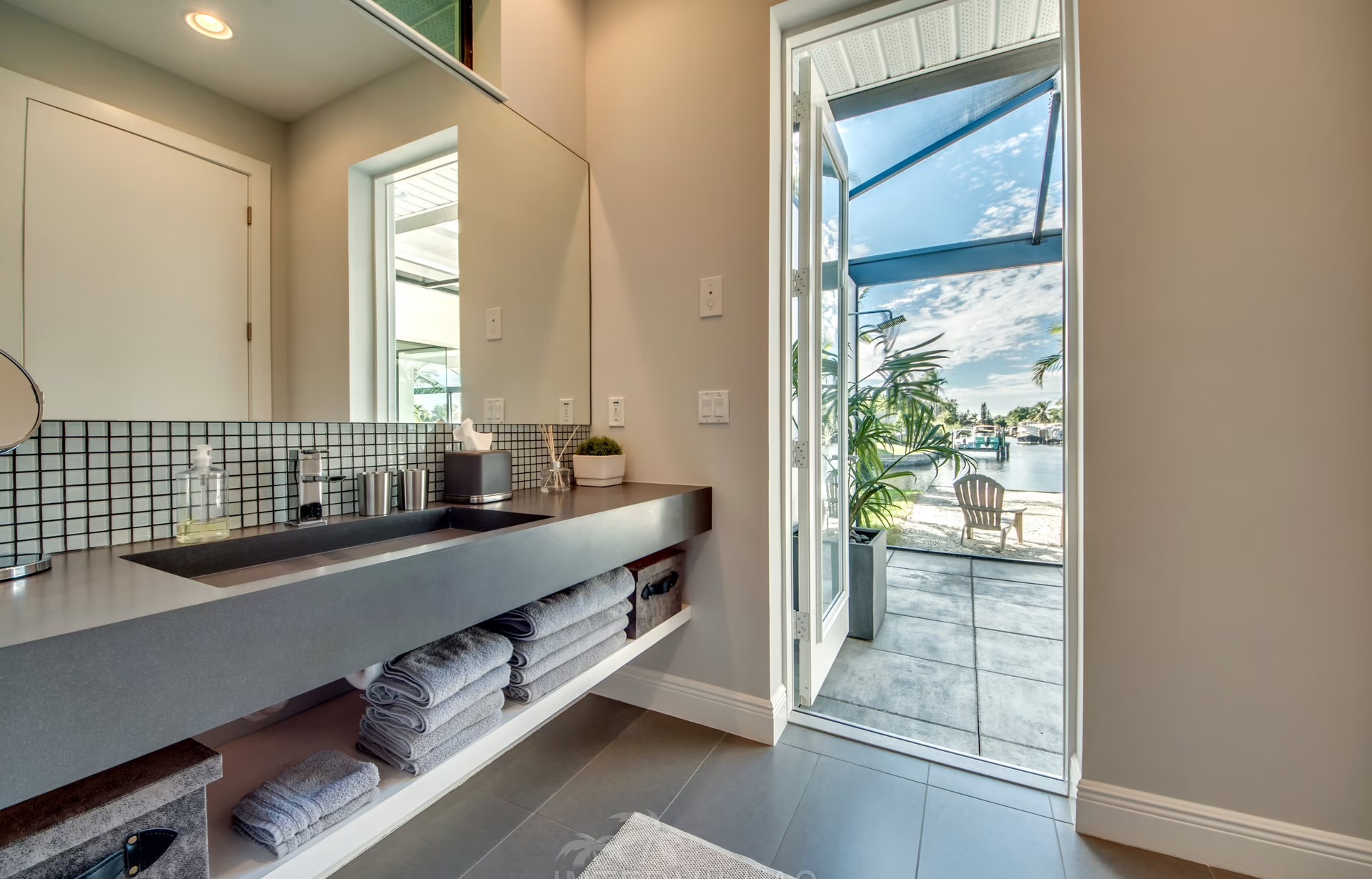 Infinity-Salzwasserpool am Wasser mit Sonnenliegen und Blick auf den Kanal.