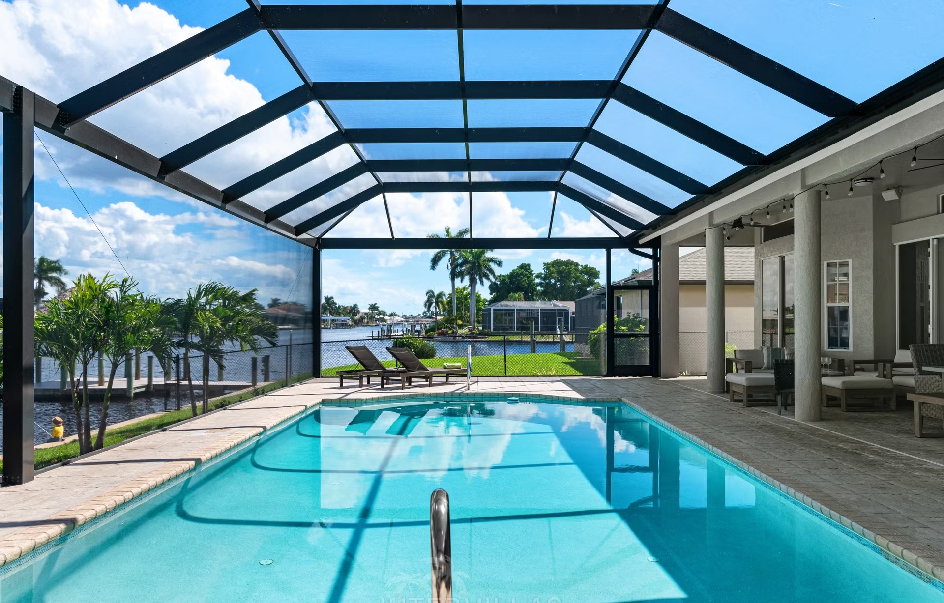Poolbereich mit Outdoorküche und Blick auf den Kanal.