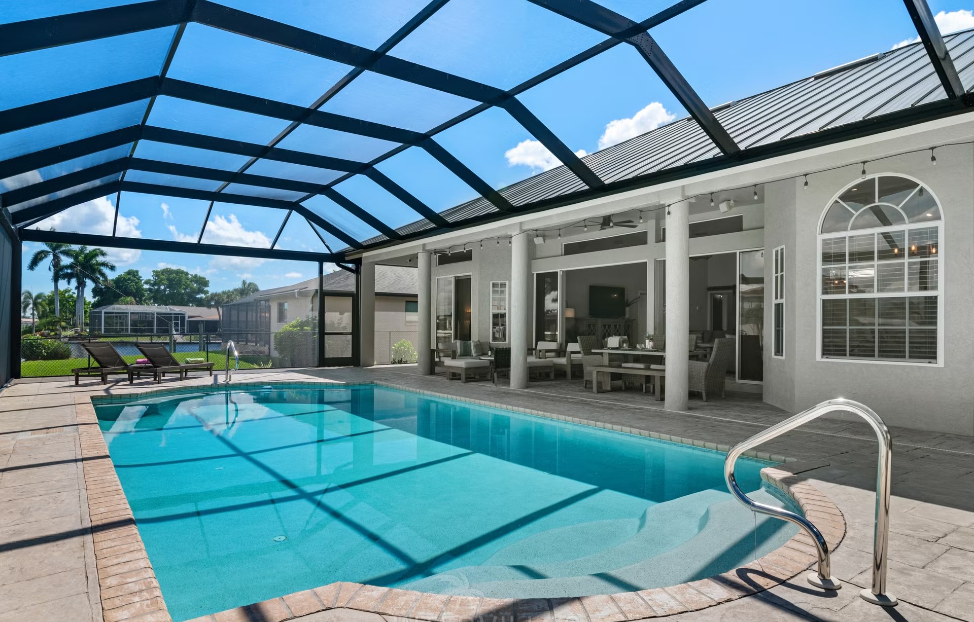 Poolbereich mit Outdoorküche und Blick auf den Kanal.