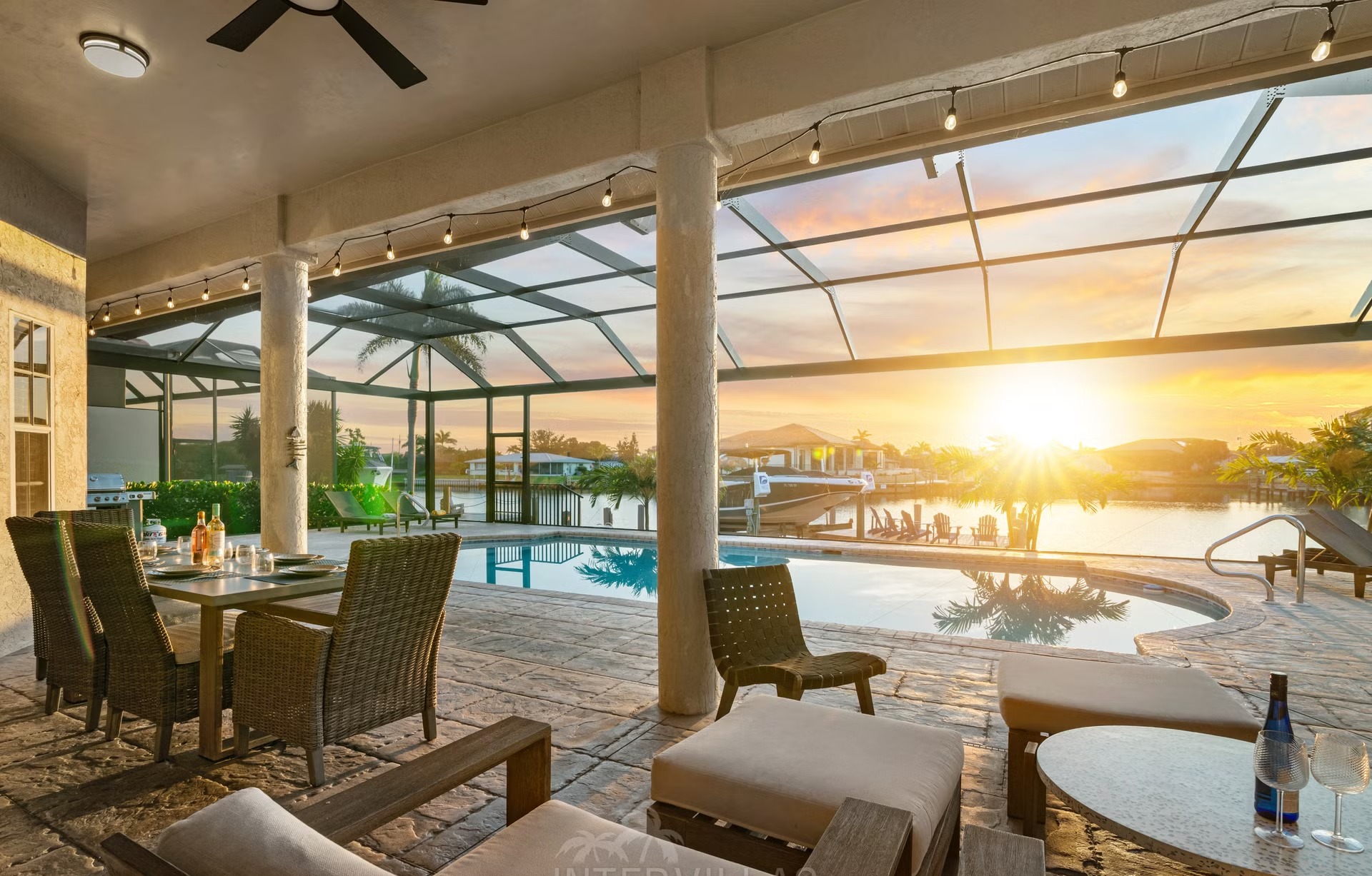 Poolbereich mit Liegen, Outdoorküche und Blick auf den Kanal.