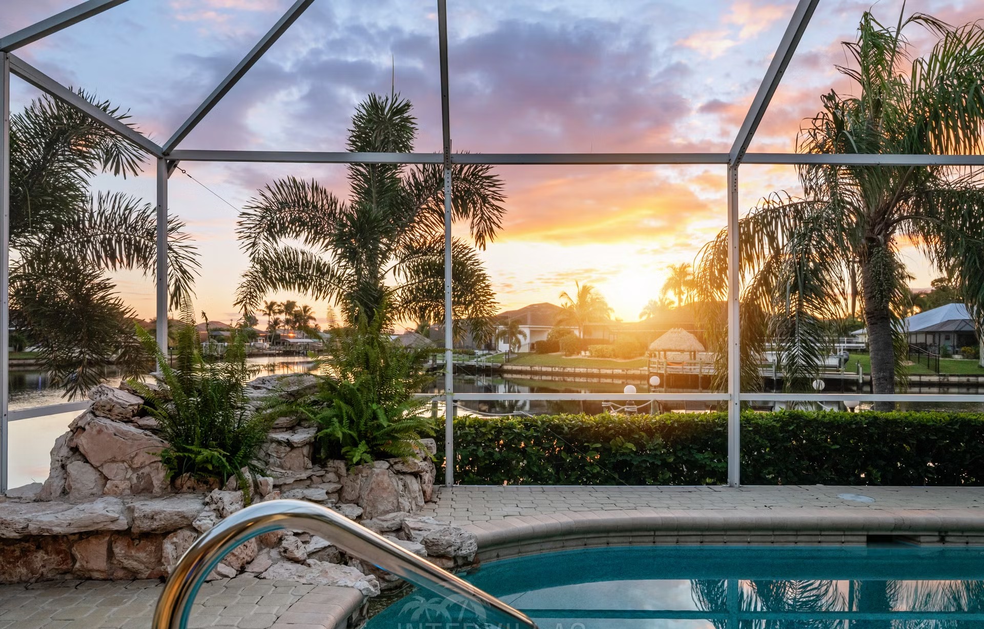 Poolbereich mit Liegen und überdachtem Sitzplatz am Kanal mit Bootssteg.