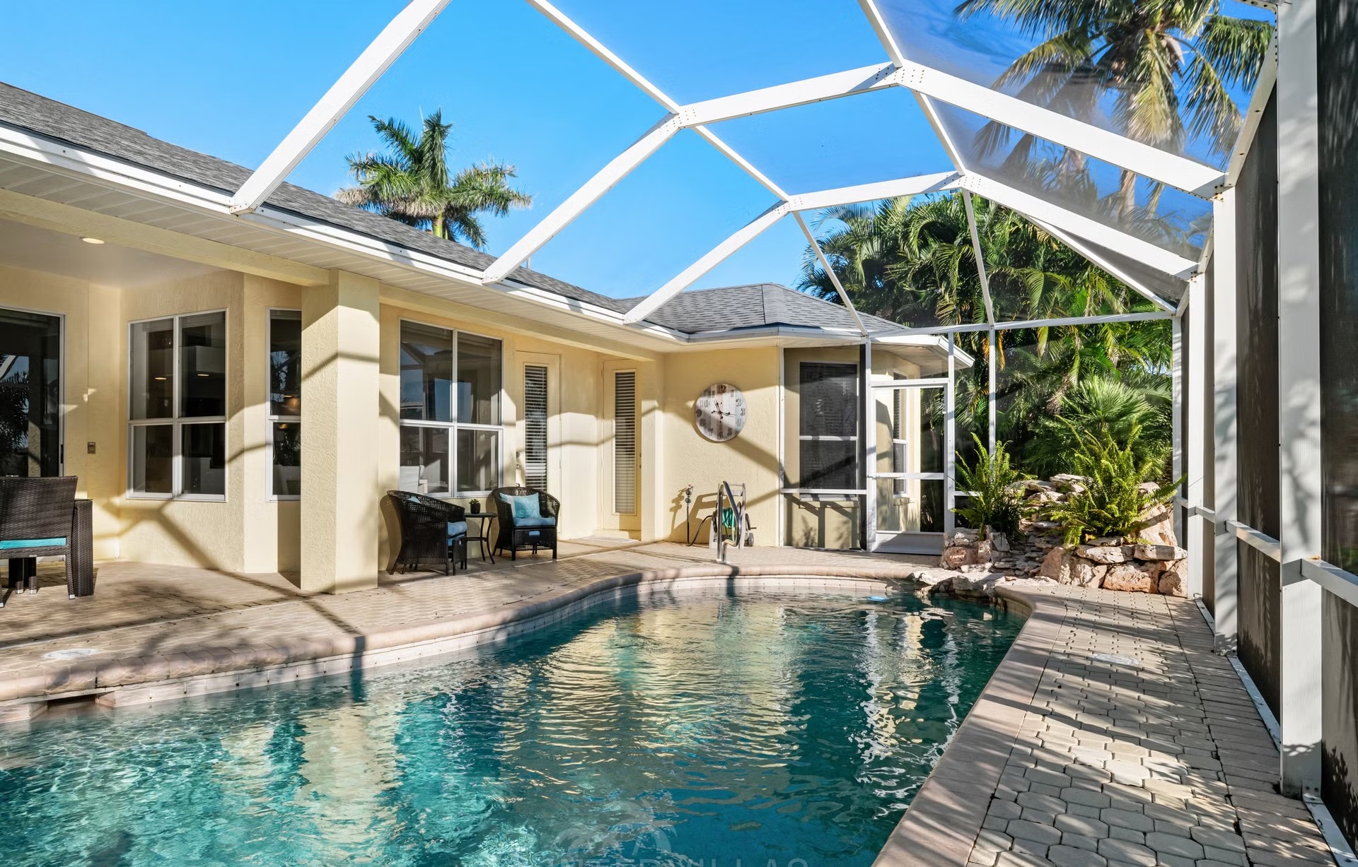 Poolbereich mit Liegen und Blick auf den Kanal und das private Dock.