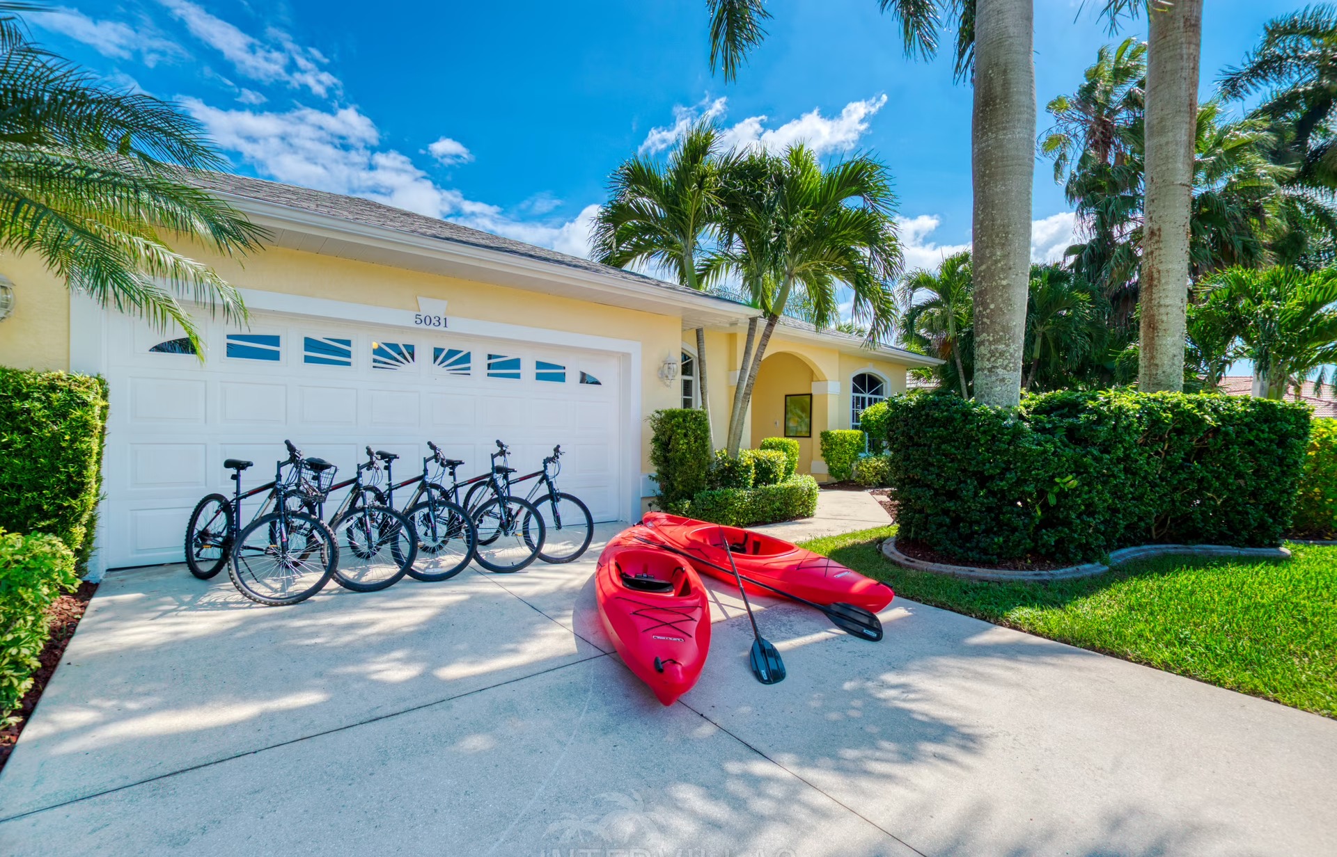 Poolbereich mit Liegen und Blick auf den Kanal mit Bootssteg und Kajaks.