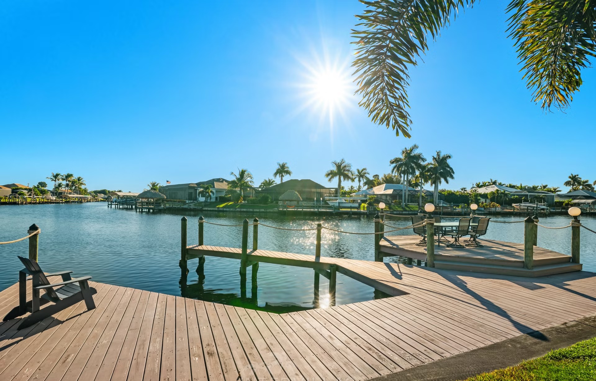 Poolbereich mit Liegen, überdachtem Sitzplatz und Blick auf den Kanal am privaten Dock.