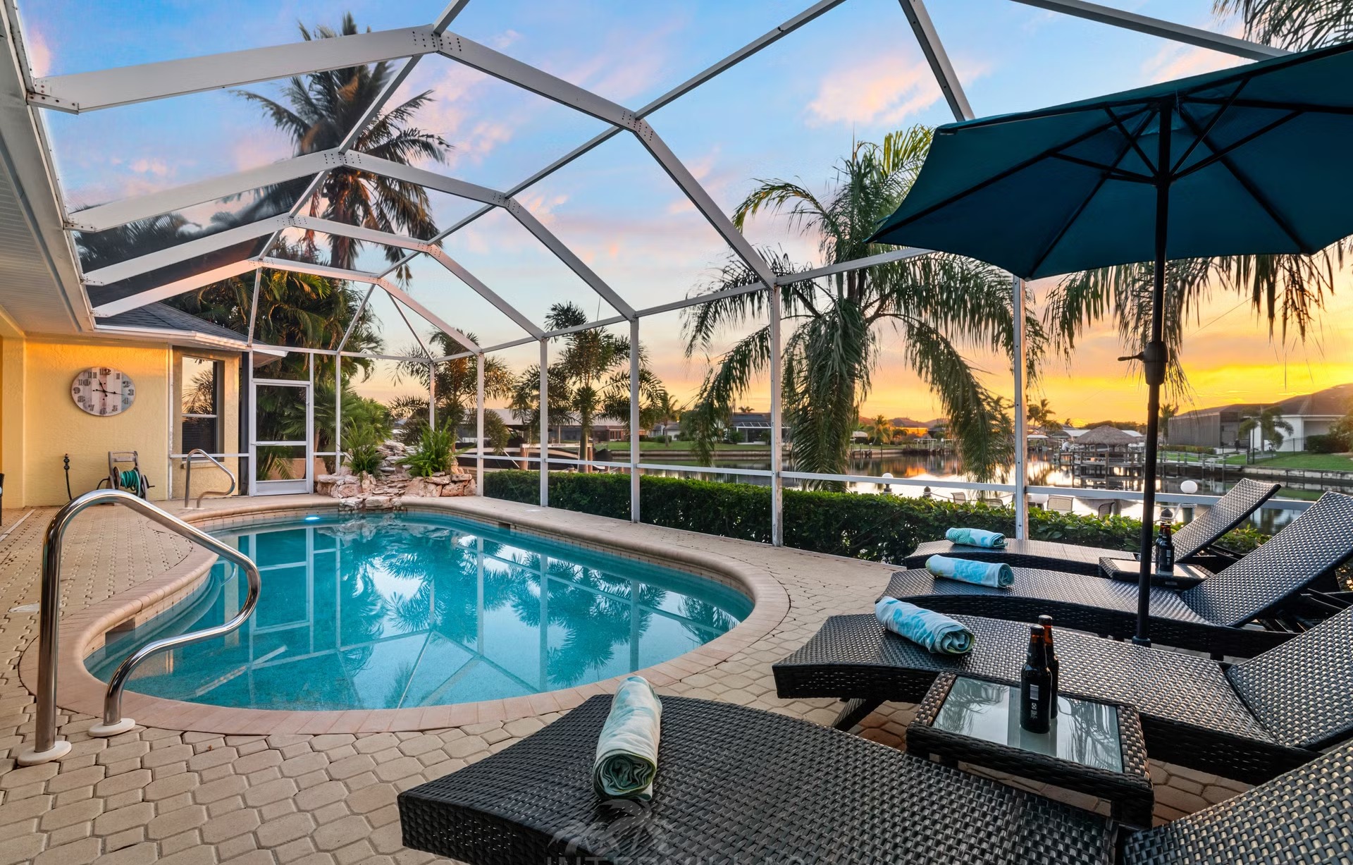 Poolbereich mit Liegen und Blick auf den Kanal am privaten Dock.