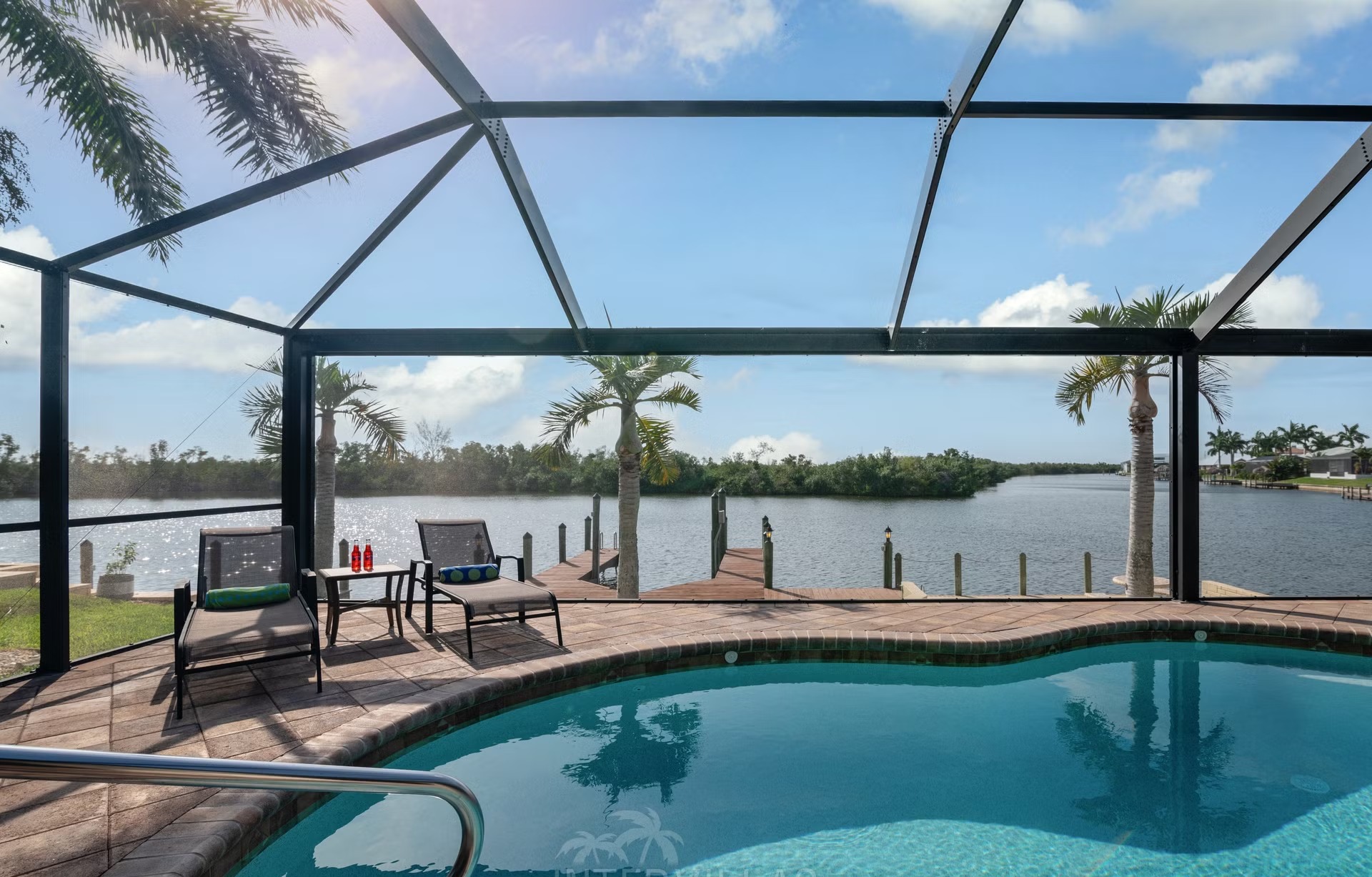 Außenansicht der Villa am Wasser mit Pool und Bootsdock.