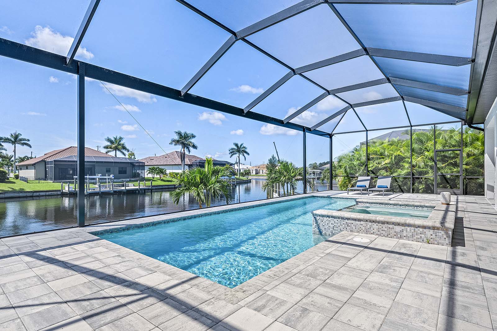 Überdachte Lanai mit Außenessbereich und Blick auf Pool und Kanal.