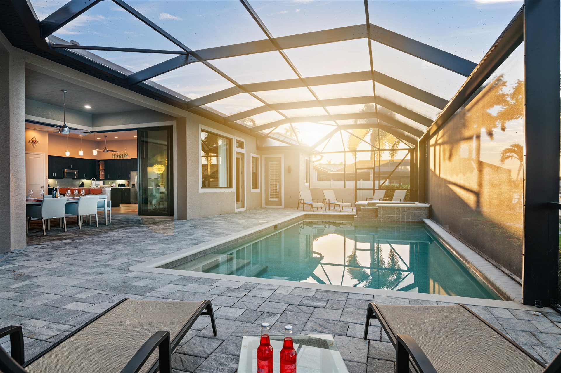Pool bei Sonnenuntergang mit Sonnenliegen und Essbereich