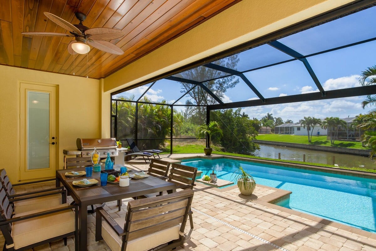 Südost-ausgerichteter Poolbereich mit überdachter Veranda, Esstisch und Grill am Kanal.