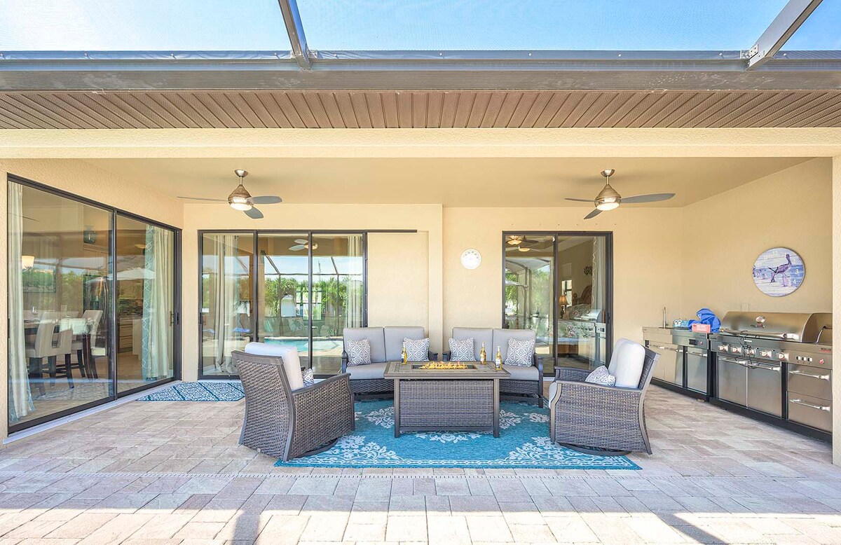 Überdachte Lanai mit Außenküche, Esstisch und Blick auf den beheizten Salzwasser-Pool.