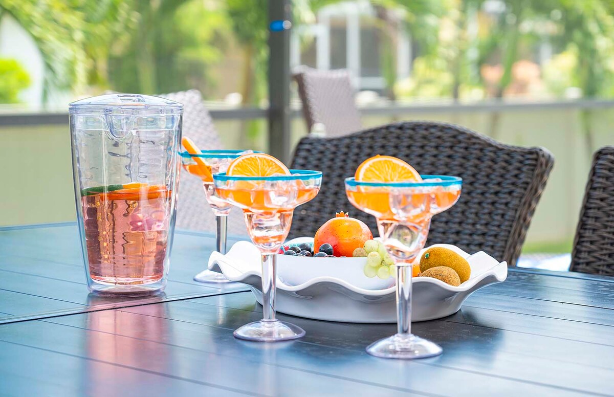 Überdachte Lanai mit Außenküche, Esstisch und Blick auf den beheizten Salzwasser-Pool.